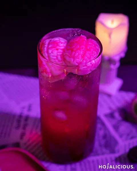 Brain shaped jello pieces floating in strawberry rose soda with sparkling bubbles, quirky party drink