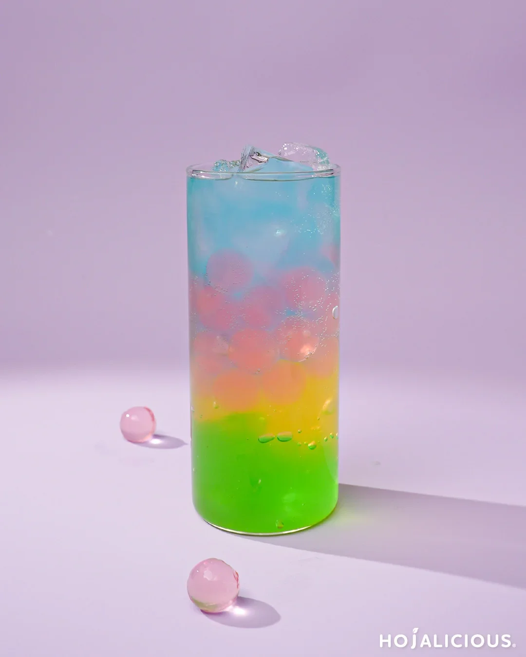 A vibrant, layered Rainbow Jelly Soda featuring colorful fruit-flavored jelly pearls, refreshing soda, and a stunning ombre effect, perfect for a playful and whimsical drink experience.