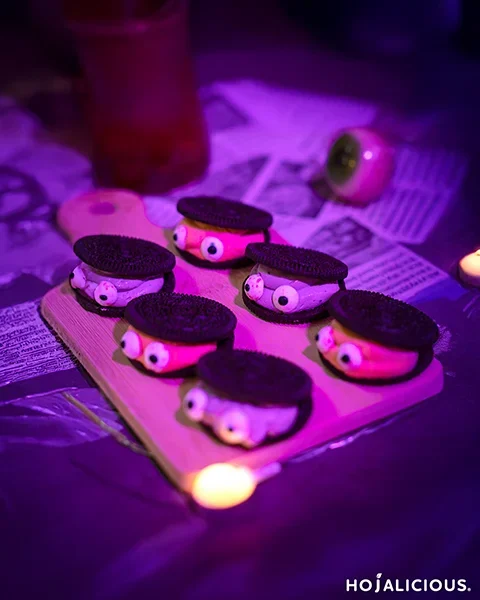 Chocolate sandwich cookie filled with pastel purple and amber creams, candy eyeballs on top, quirky monster dessert