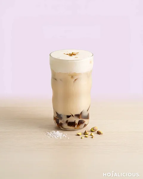 Jin Xuan milk tea with Jin Xuan tea jelly, sea salt cream foam, and crushed pistachios served in a transparent cup.
