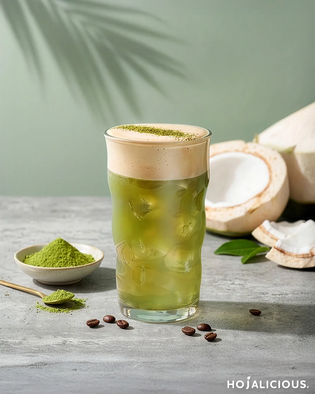 A layered iced matcha coconut drink topped with silky Blue Mountain coffee cream foam, featuring vibrant green tea color, tropical coconut notes, and a smooth café-style presentation.