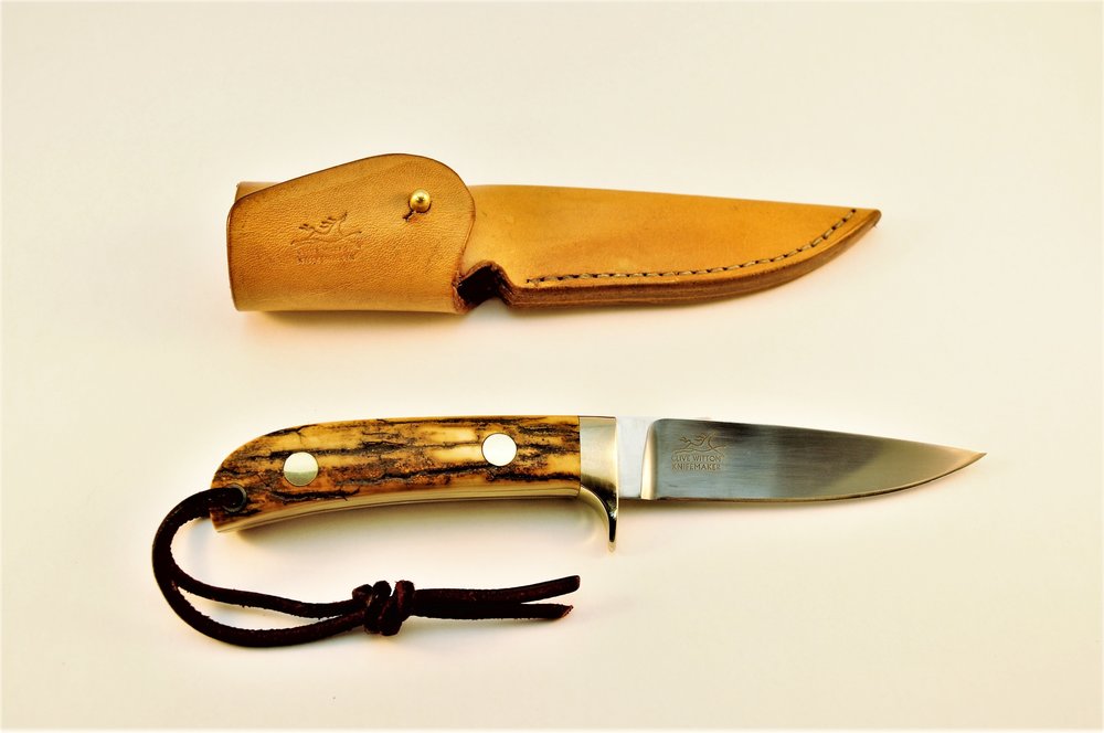 95mm Drop PointIt has a hollow-ground, drop point blade 3 3/4″ long and 0.130″ thick with a distal taper to the point and through the tang. The handle is beautiful Mammoth Ivory, which is approximately 100,000 to 150,000 years old, and the guard and…