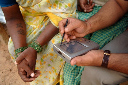A produce buyer using a ‘Simputer’ to negotiate a price with the farmer's wife.