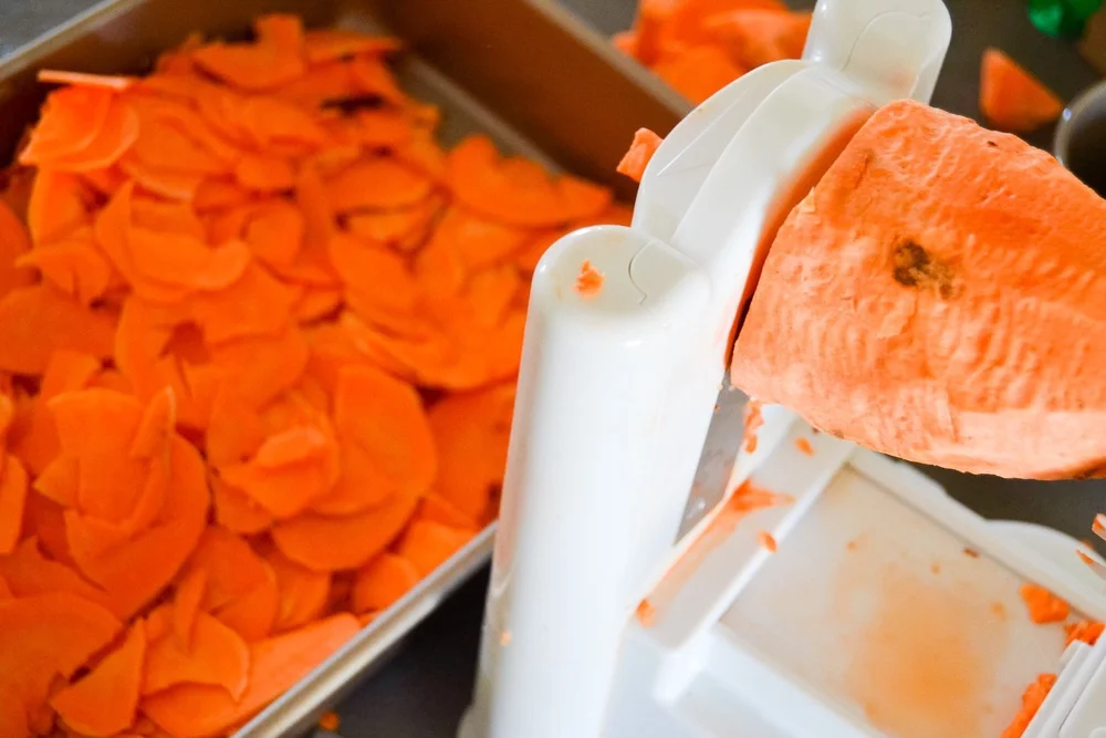Using a spiral slicer to evenly and quickly slice the sweet potatoes