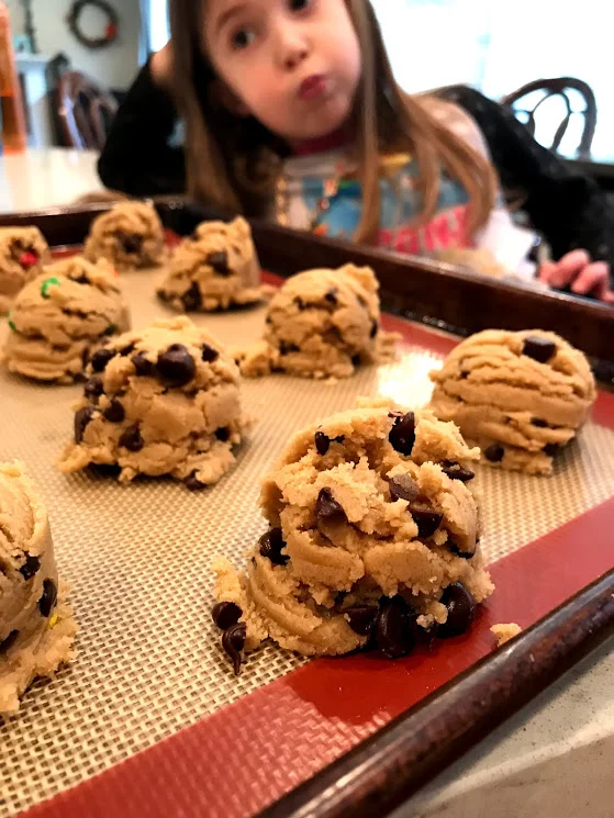 Scoop the cookies out and place them on a parchment or silicone mat lined cookie sheet. Also, I love my daughter's expression here, she is doing exactly what I feel inside, "Are the cookies ready yet?"