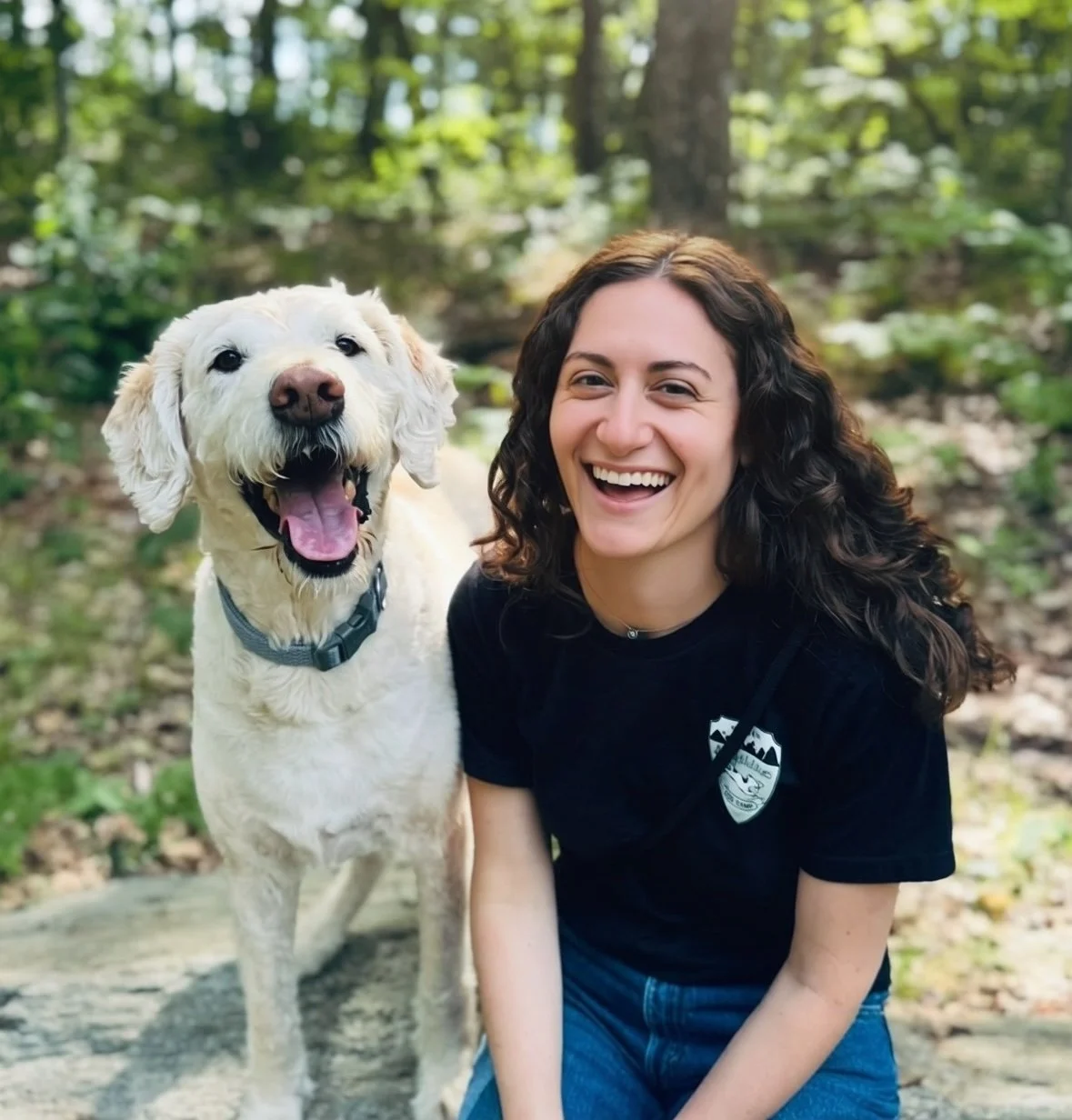Sophie Greenberg, Client Relations Manager at Far Fetched Acres, smiling outdoors beside a happy cream dog.