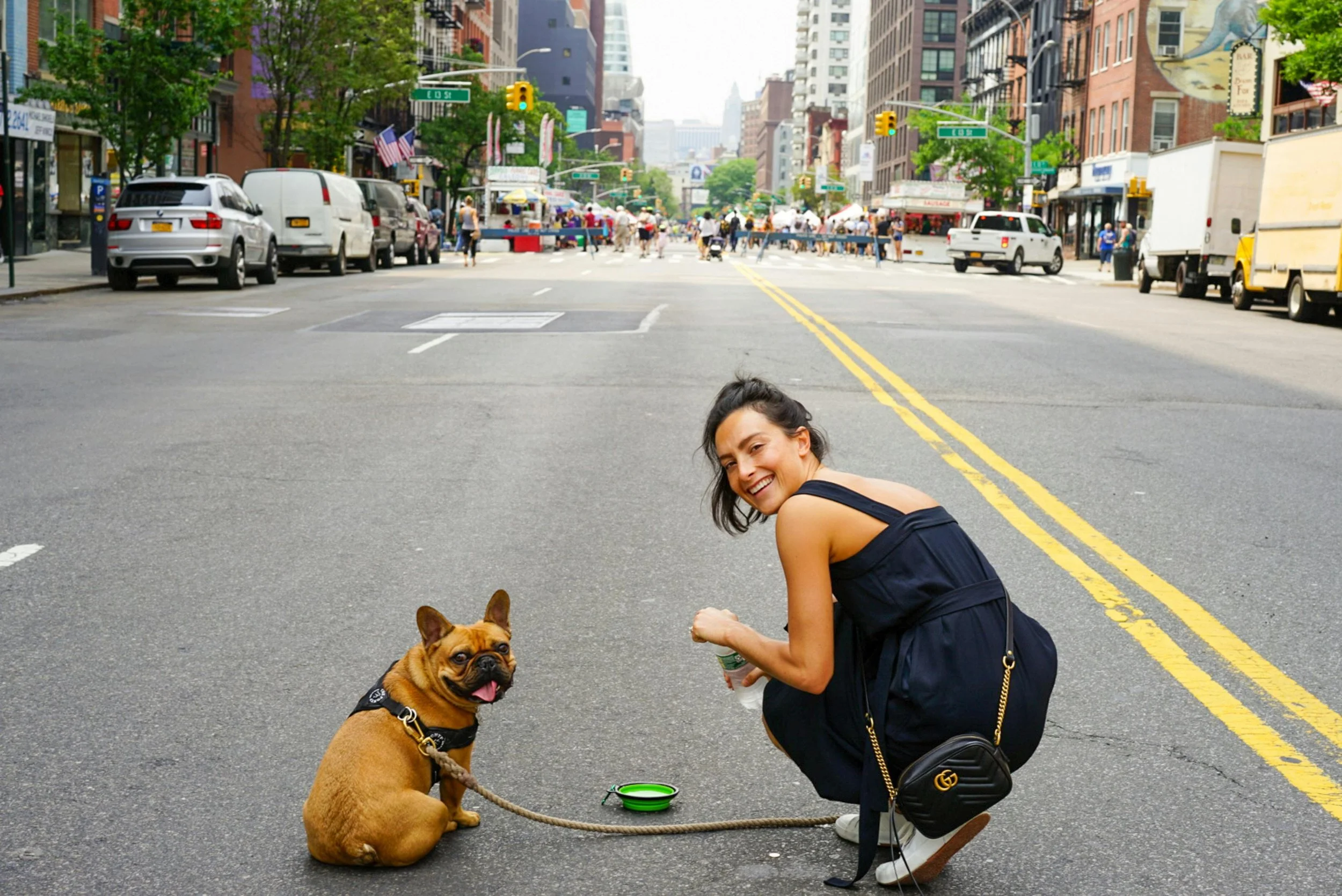 A woman walking her puppy in New York City in the summer