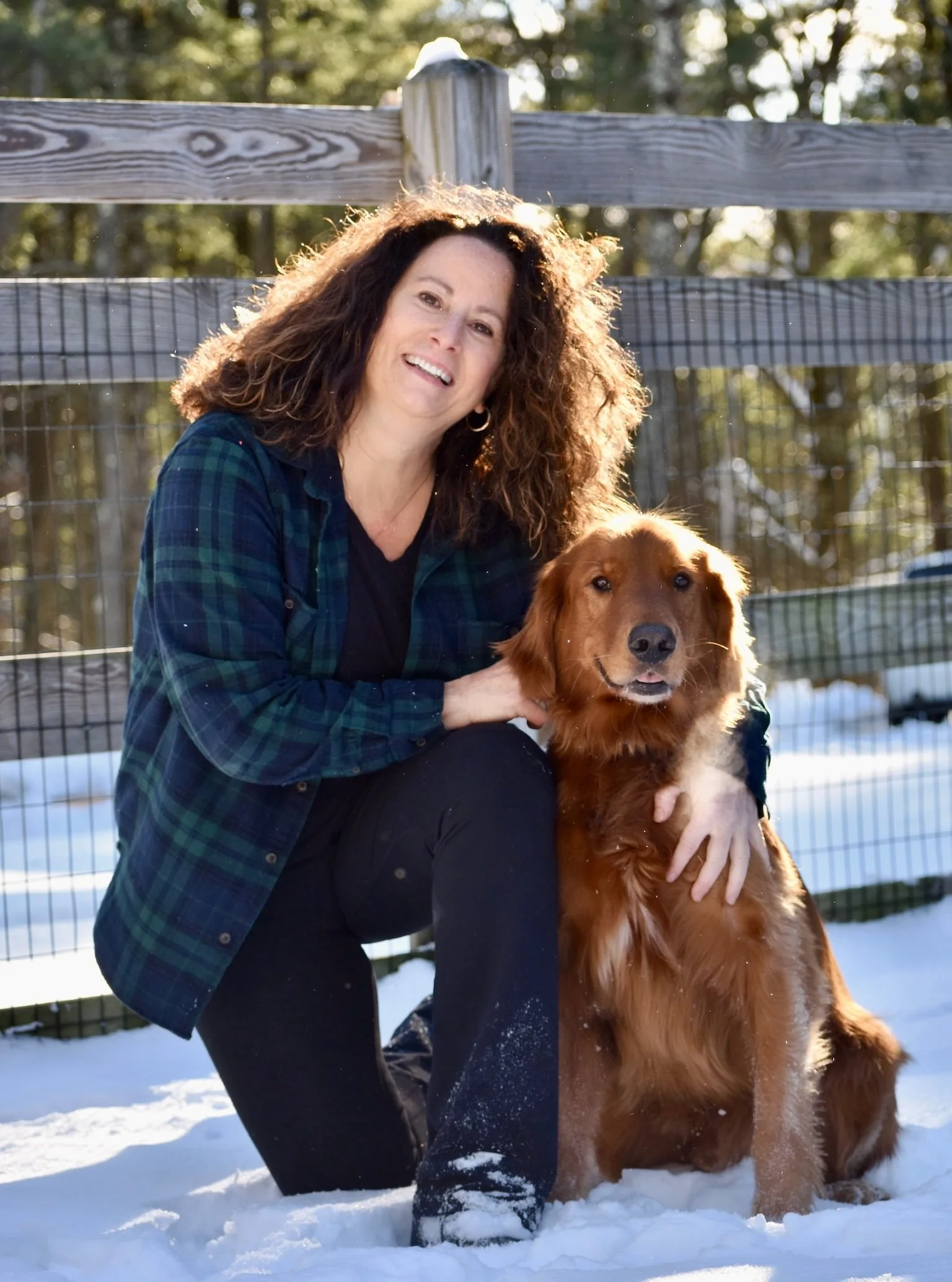 Sue Geel, General Manager at Far Fetched Acres, smiling outdoors in a snowy setting with a golden retriever.
