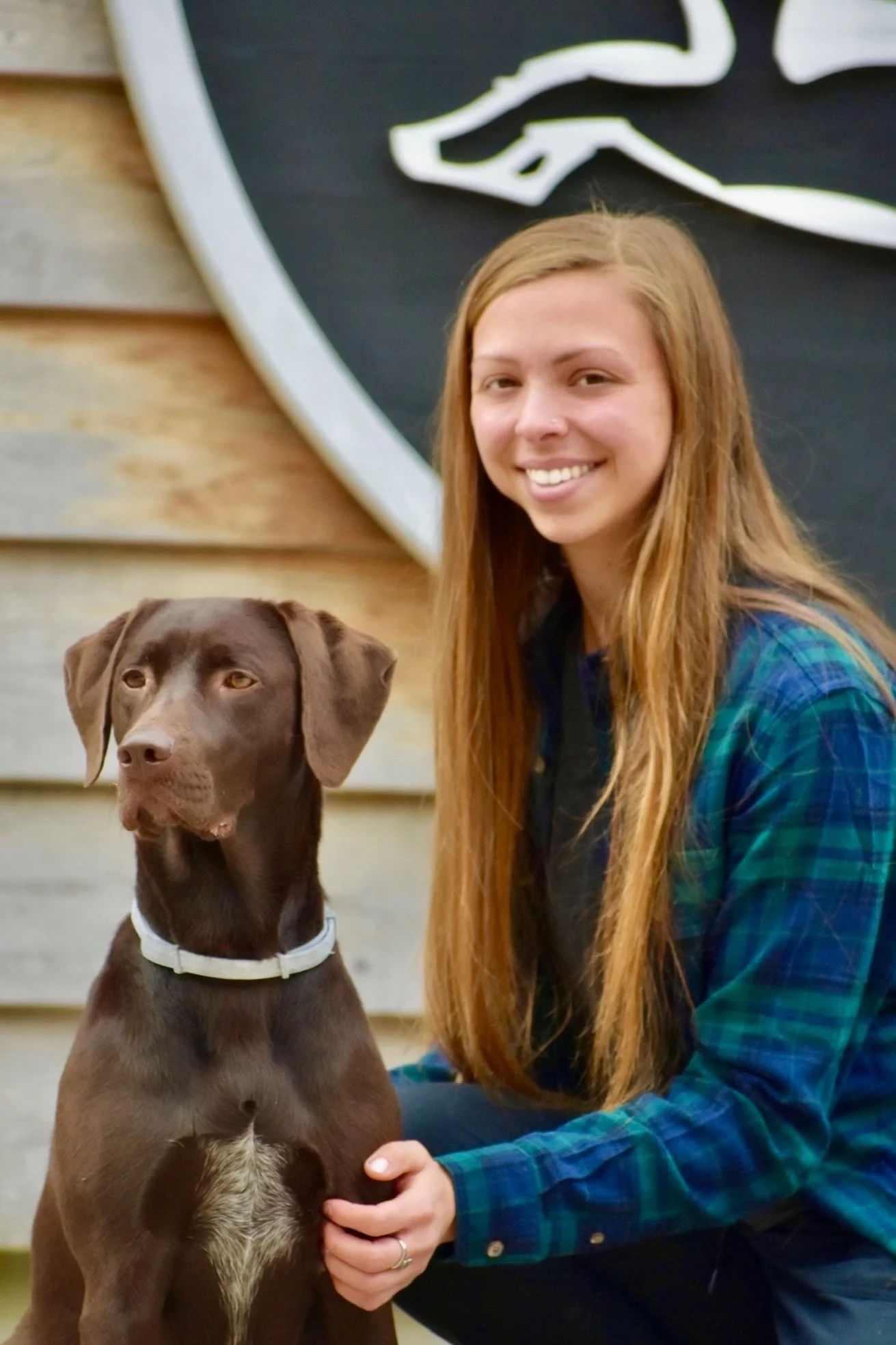 Jayme Spencer, Camp Director at Far Fetched Acres, smiling outdoors while seated beside a dog.