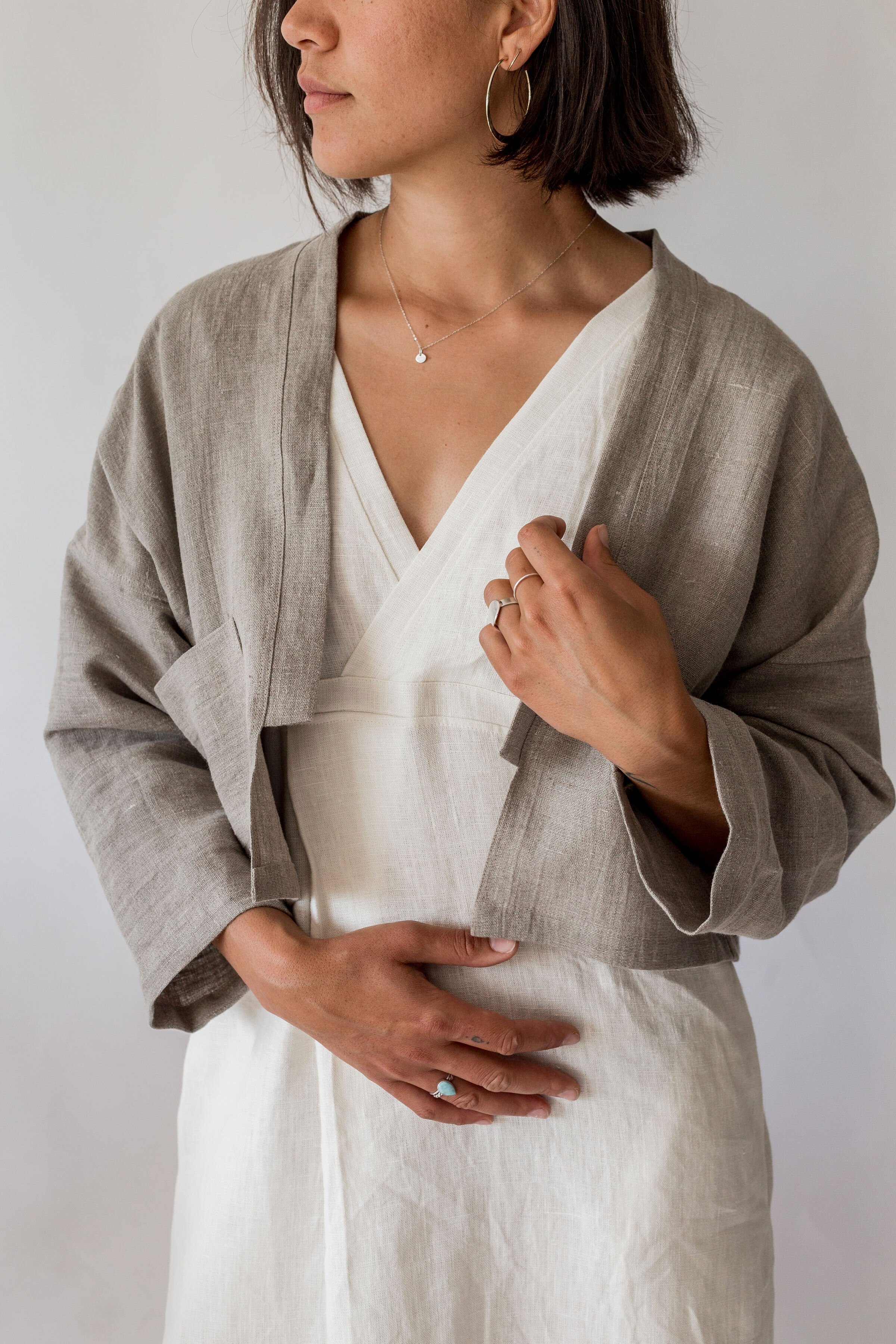 close up of woman wearing ann linen jacket with cropped open front and single pocket in natural