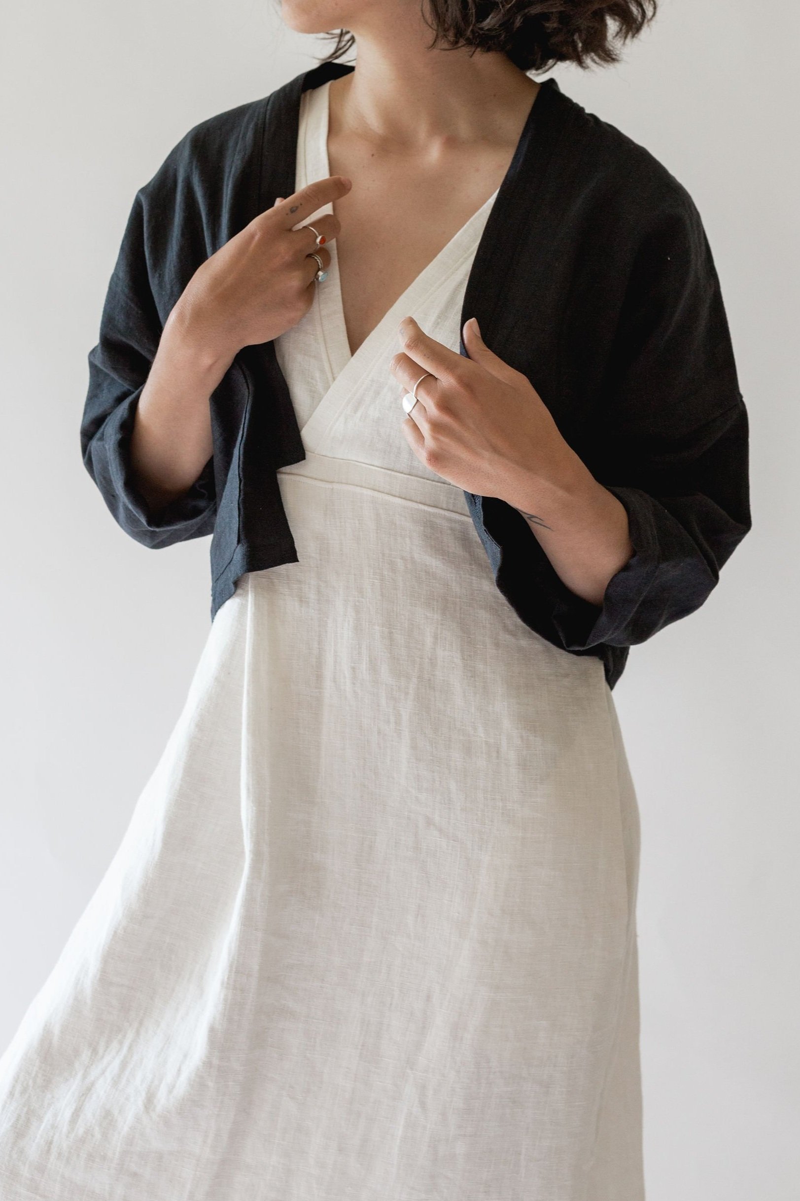 woman wearing ann linen jacket with cropped open front and single pocket in black