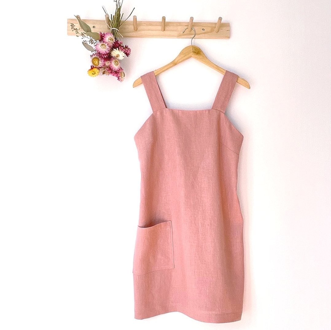 The Carmen Dress: a playful, linen mini-dress with a unique front and back neckline, designed for both style and comfort. An elastic insert keeps straps in place, perfectly covering bra straps for a sleek look. Featuring a practical pocket and a hem 