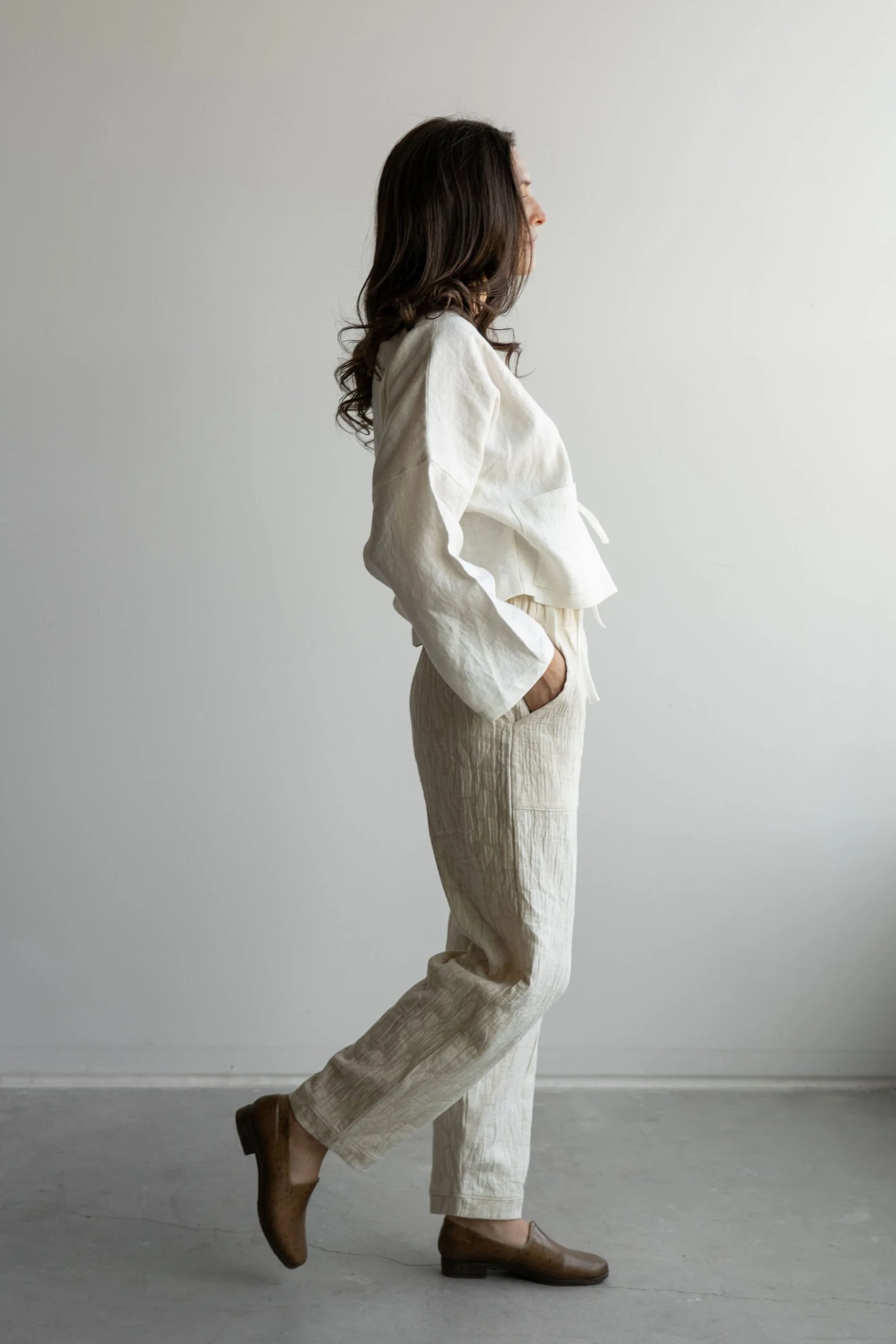 Side view of woman wearing Long-sleeve linen wrap top in Ivory