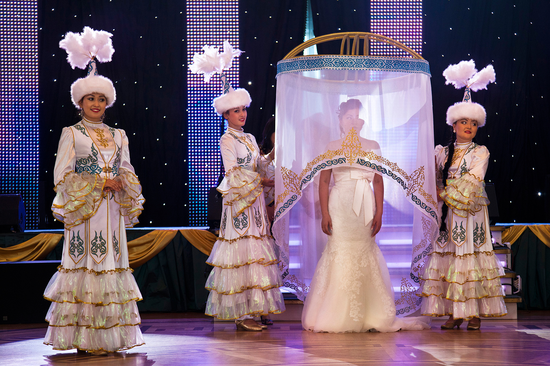  Flanked by traditional Kazakh dancers, a bride awaits her formal unveiling at an opulent wedding palace, where she has just been married in a ceremony capped by the release of two white doves. The revelry begins when the veil is lifted.  Astana, Kaz