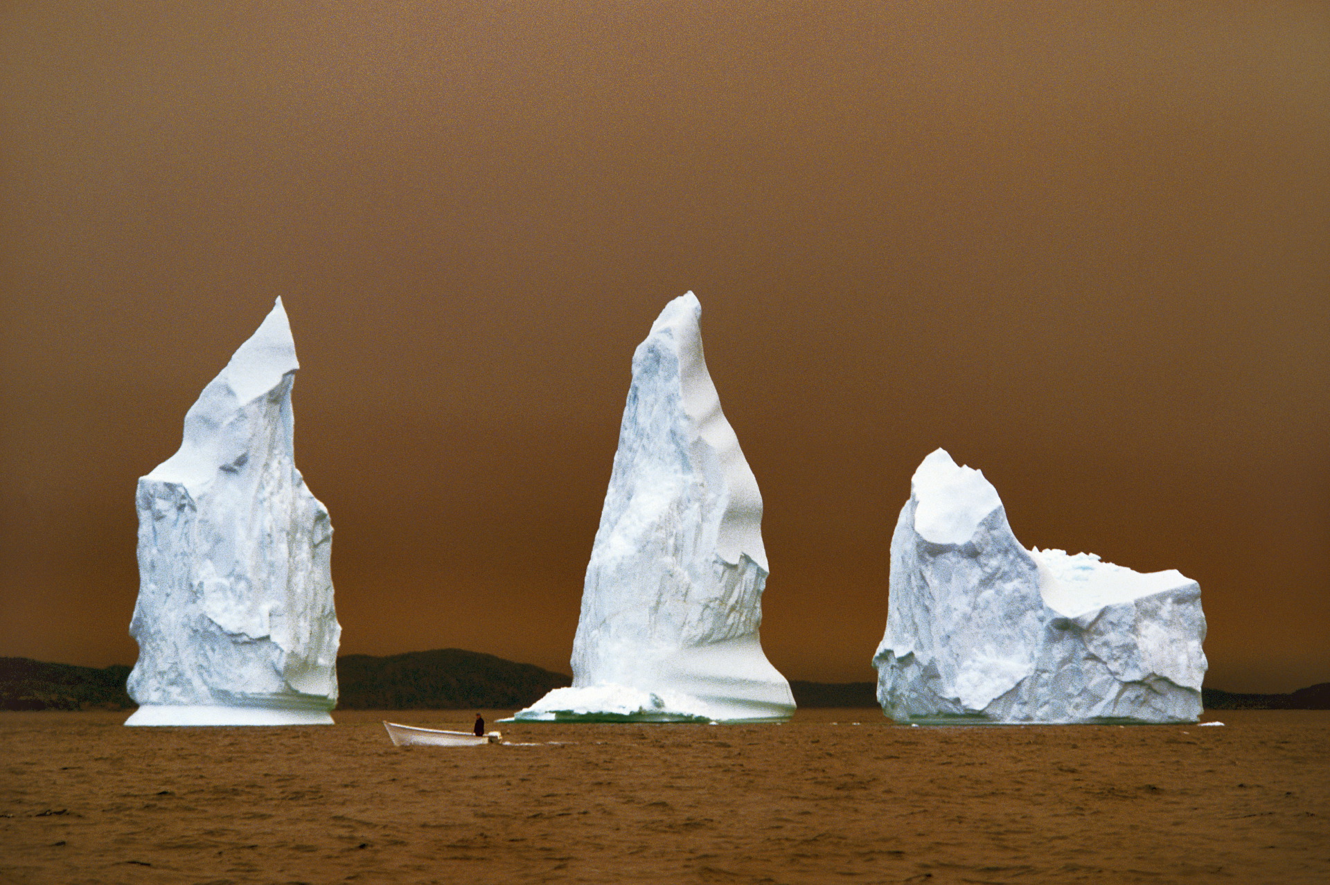  A trio of icebergs cast in the eerie glow of a nearby forest fire in "The Iceberg Capital of the World."  Twillinggate, Canada  