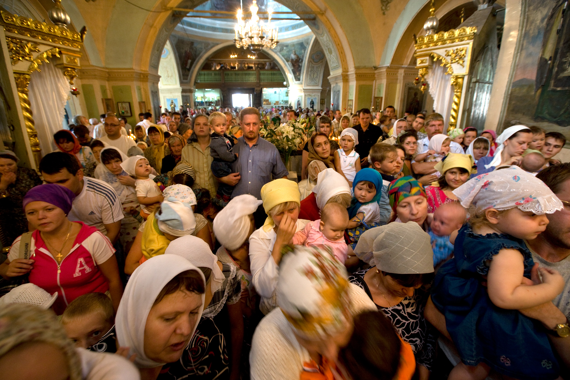  New generations of believers pack into the ornate spaces of Znamensky Cathedral for the feast day of the Transfiguration.  Tyumen, Russia  
