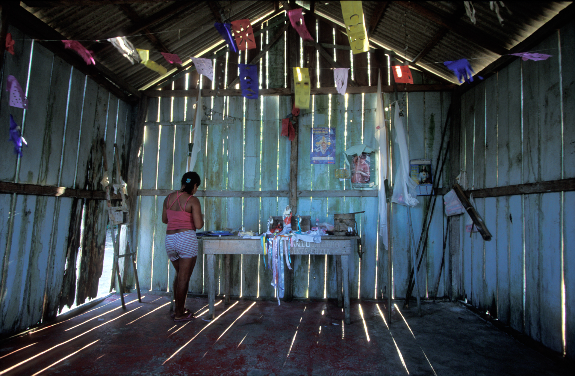  In the village of Niteroi in Kwata-Laranjal, a woman prepares the altar of a makeshift church for a ceremony honoring the patron of the village. Many of the Munduruku have converted to Christianity.  Niteroi, Brazil  