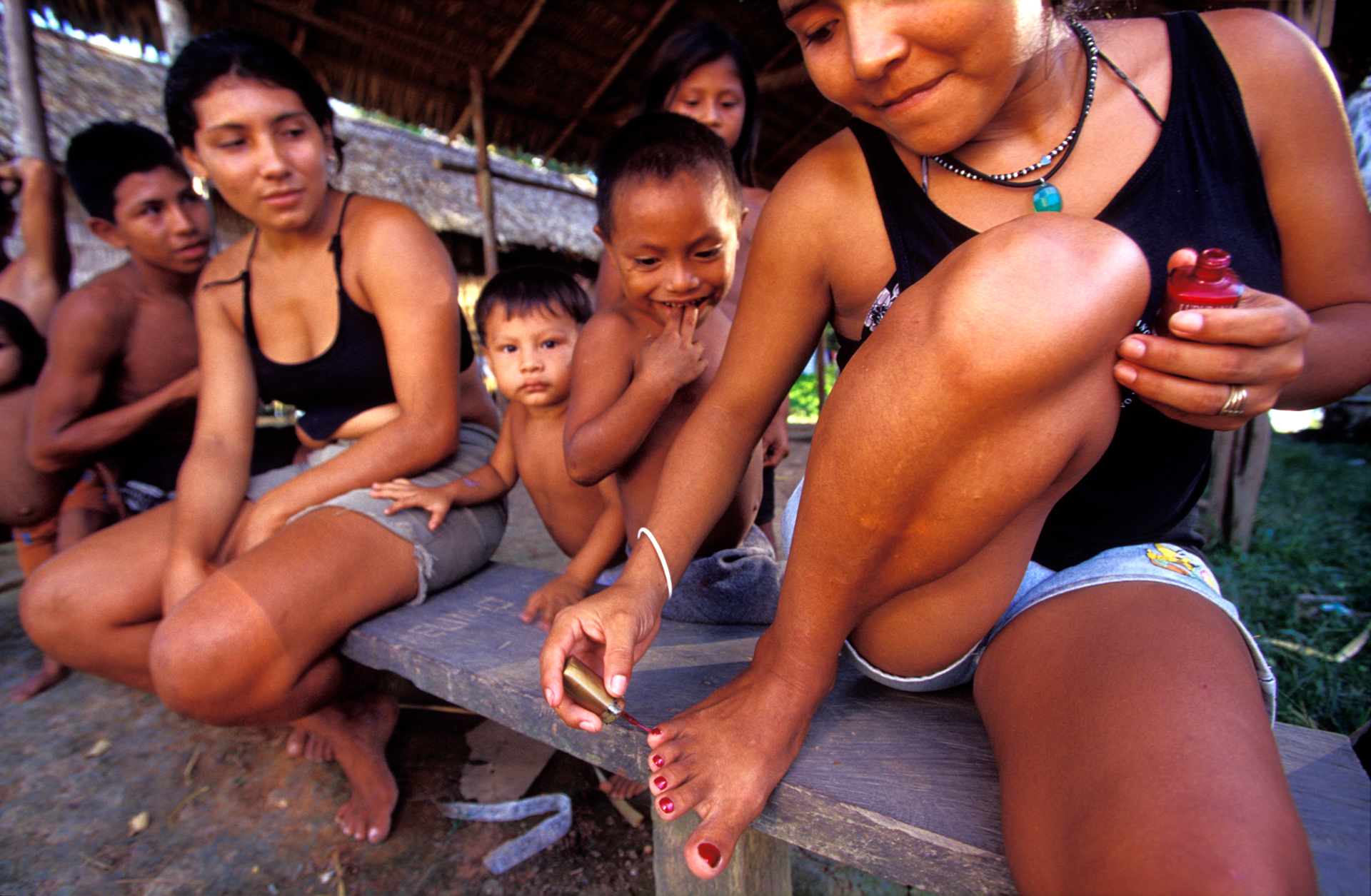  A young Indian girl proudly paints her toenails in public. Avon products are among the few luxury items accessible in the smaller communities around the Rio Cunuma.  Kwata, Brazil  