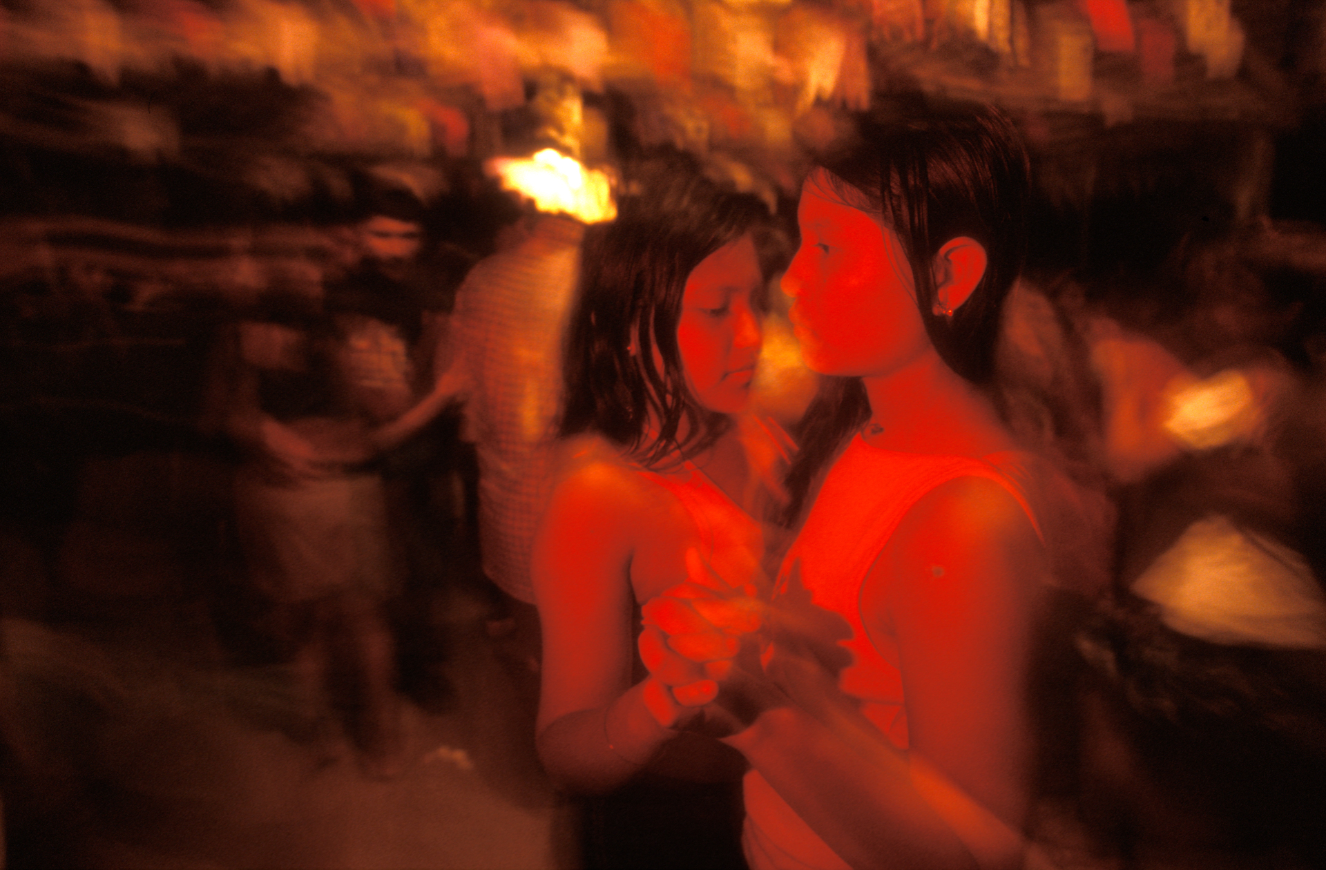  Western cultural influences dominate the "Disco Night" in Niteroi, as two young Indian girls slow dance to the sound of music, blasting from a simple set of speakers.  Niteroi, Brazil  