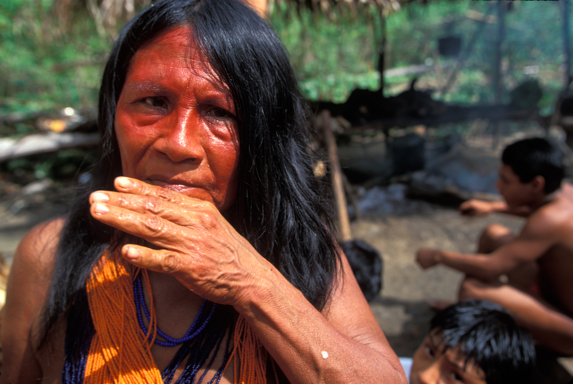  Paroripa, the village chief's wife, wipes her face after a feast. She wears the traditional 10 meter long Waiapi necklace made of approximately 4,000 beads.  Aramira, Brazil  