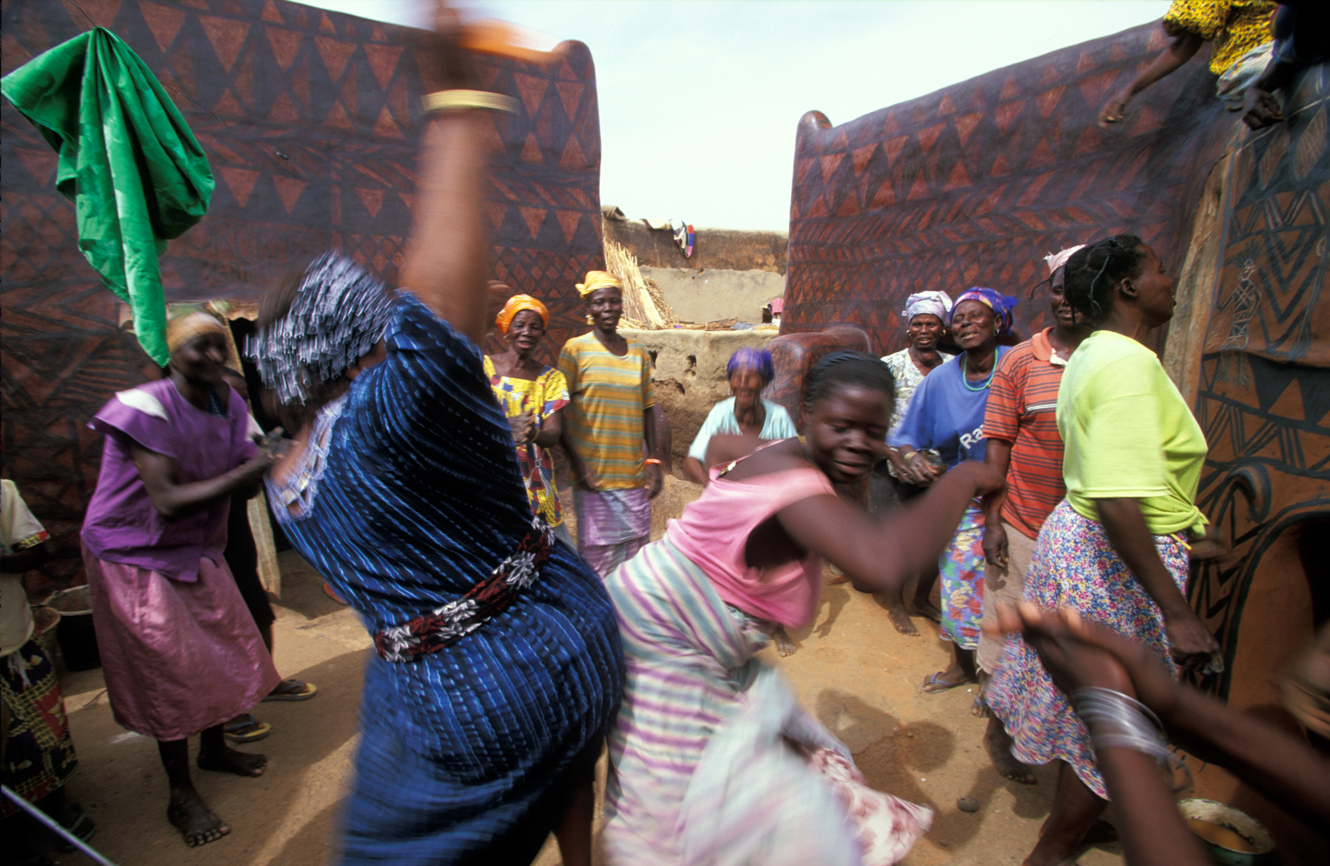  During the mural competition in Tiebélé, the Gurunsi women of Burkina Faso take a break to dance, sing, and do "the bump."  Tiebélé, Burkina Faso  