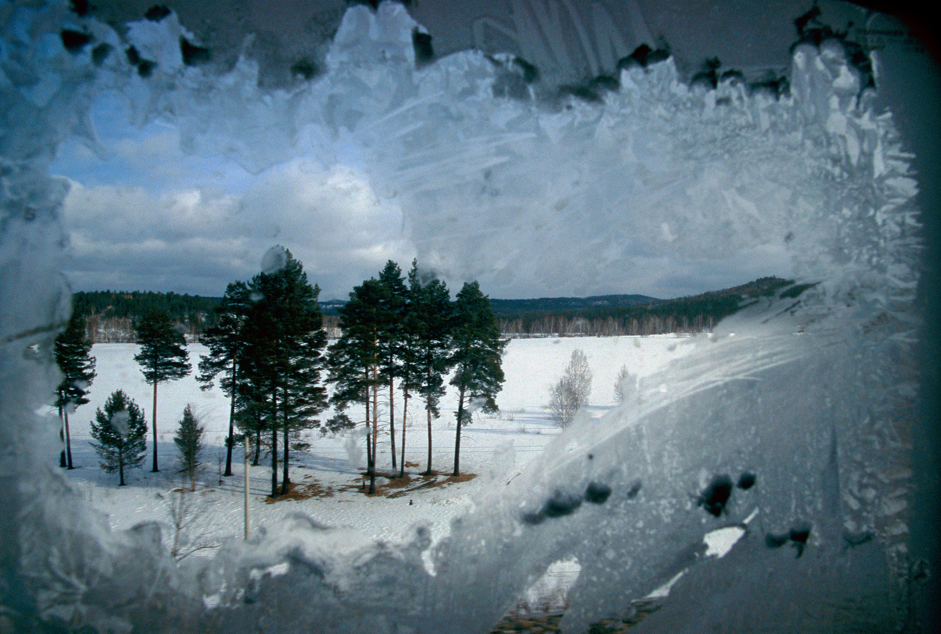  Endless trees and the frozen silence of the Russian taiga slide past the frosted window of the Trans-Siberian Railroad as it sweeps east of Lake Baikal.  Siberia, Russia  