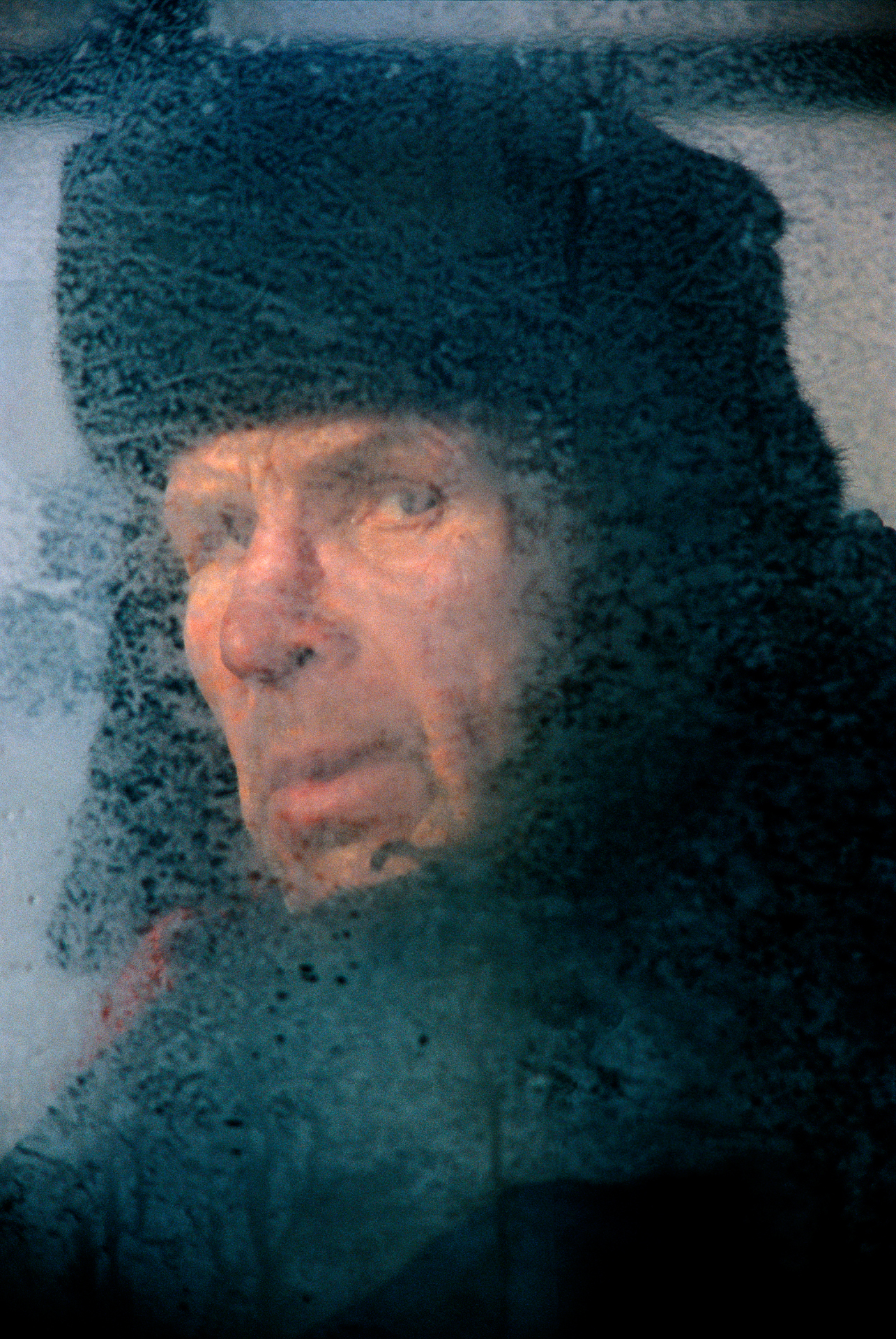  In south-central Siberia, biting cold frosts the windows of an electrichka, a local electric train, where a passenger sports the classic Russian defense against winter – a fur shapka.  Krasnoyarsk, Russia  