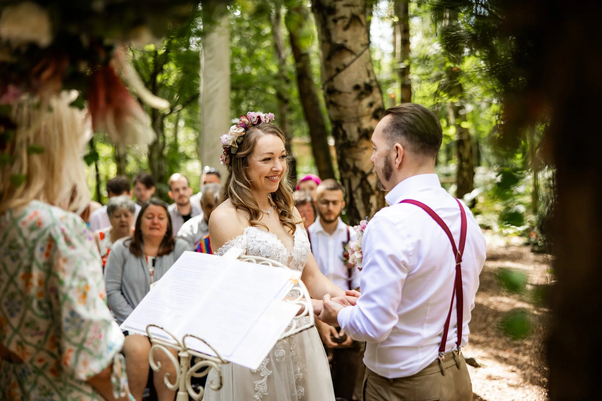 Bride and groom exchanging vows in a forested wedding ceremony surrounded by guests at Cheshire Woodland Weddings.