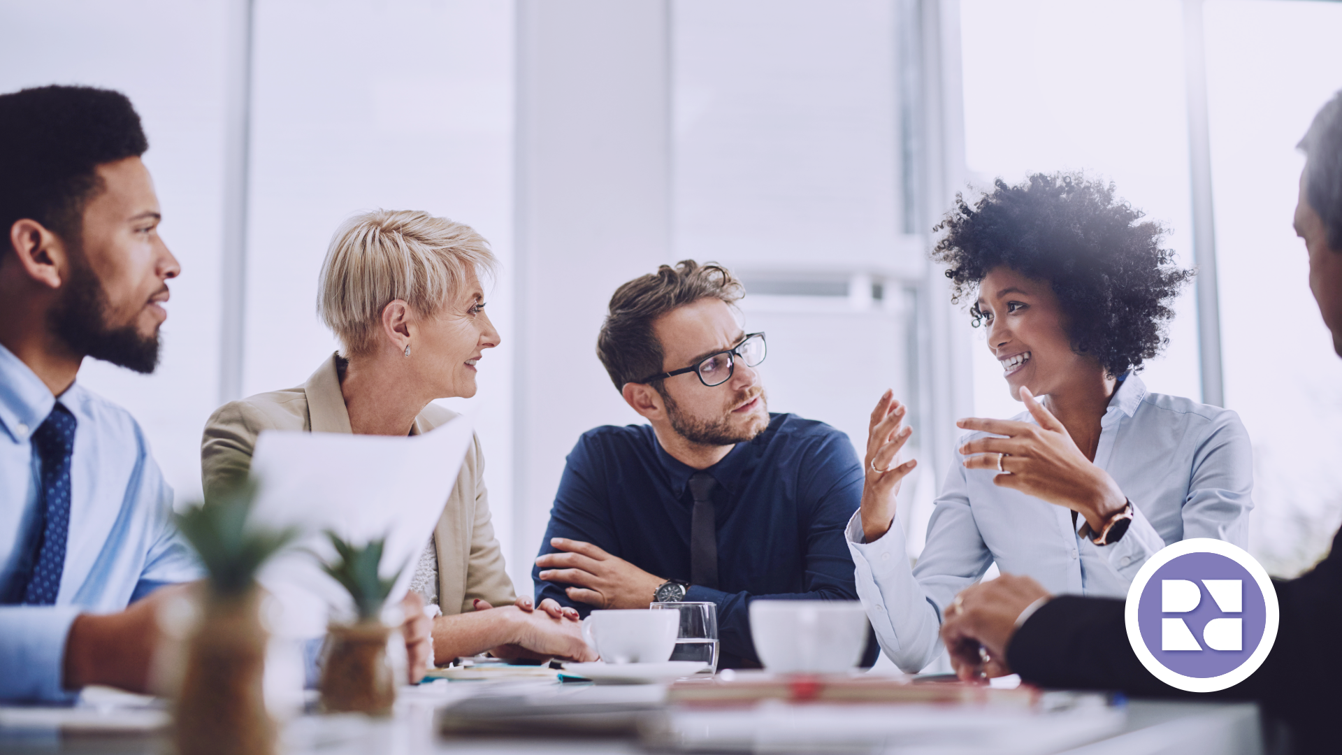 Diverse group sitting around a conference table listing to their nonprofit consultant