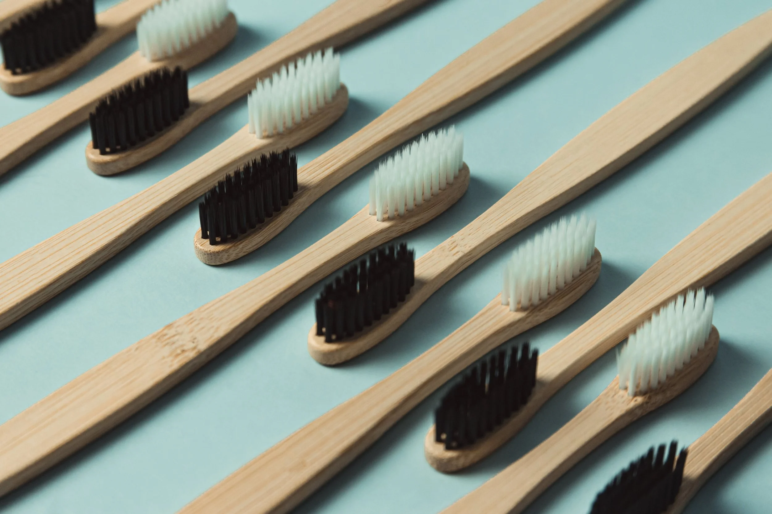 wooden-toothbrushes-lined-up-against-a-green-background.jpg