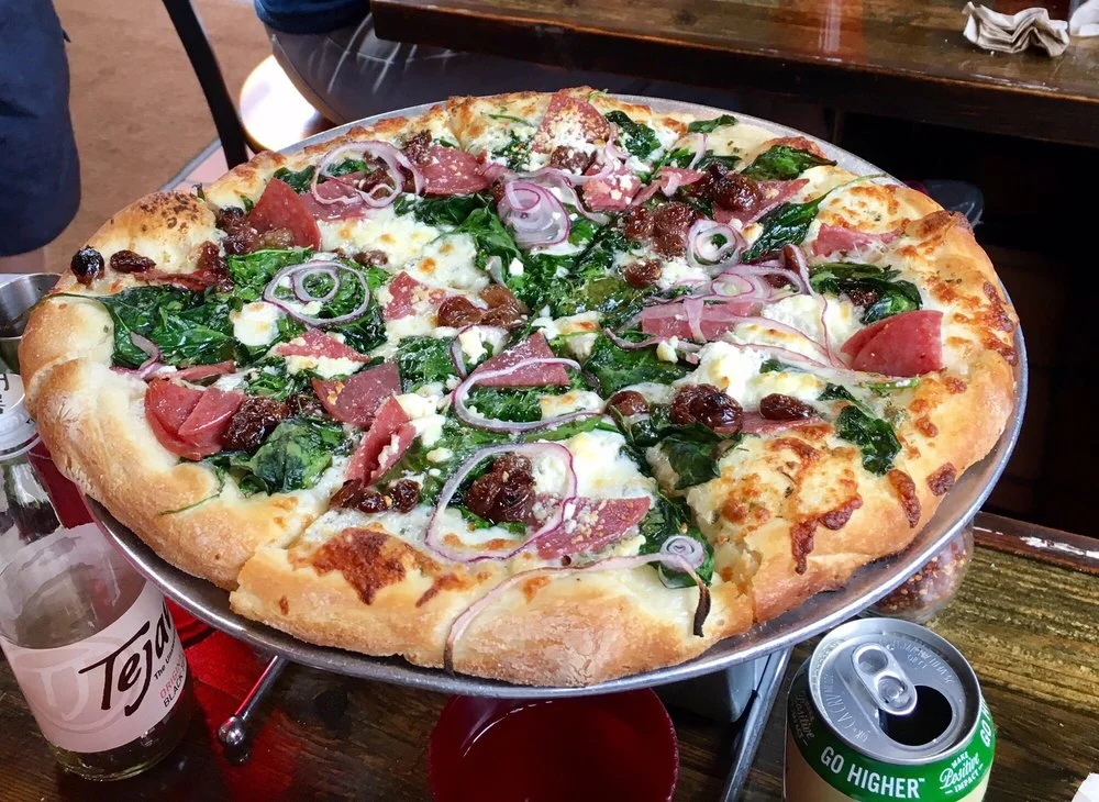 Bacchanalia - garlic oil base with mozzarella, spinach, salami, roasted red grapes, red onion, and chevre