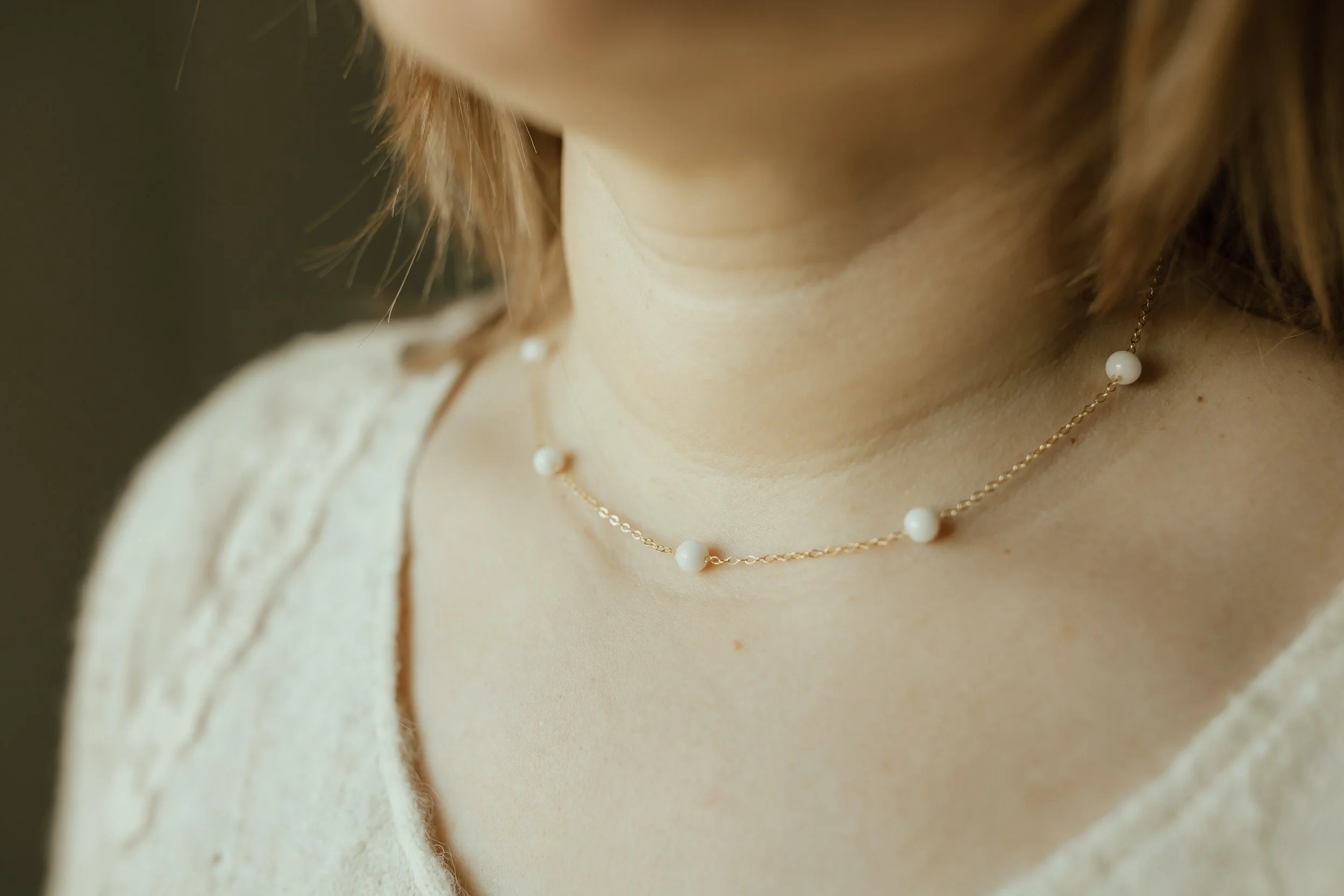 Woman wearing a yellow gold petite pearl choker with 6 pearls spaced out