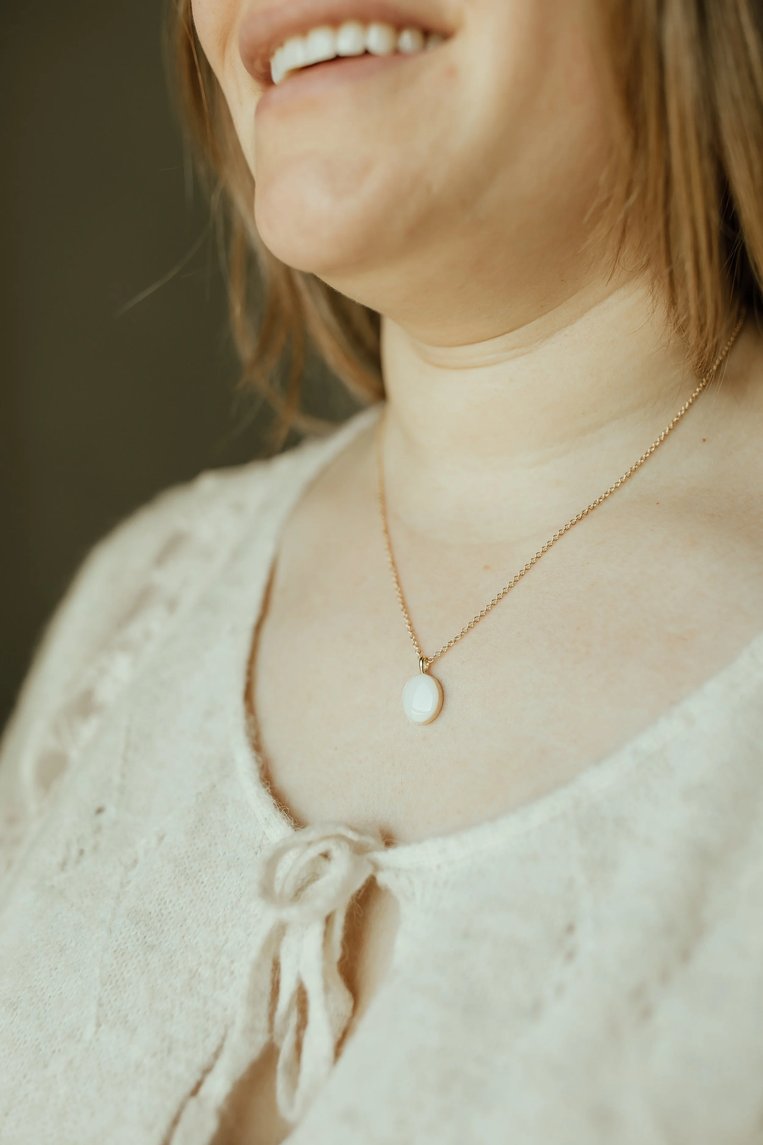 Woman wearing Solid Yellow Gold Heirloom Oval necklace made with breastmilk