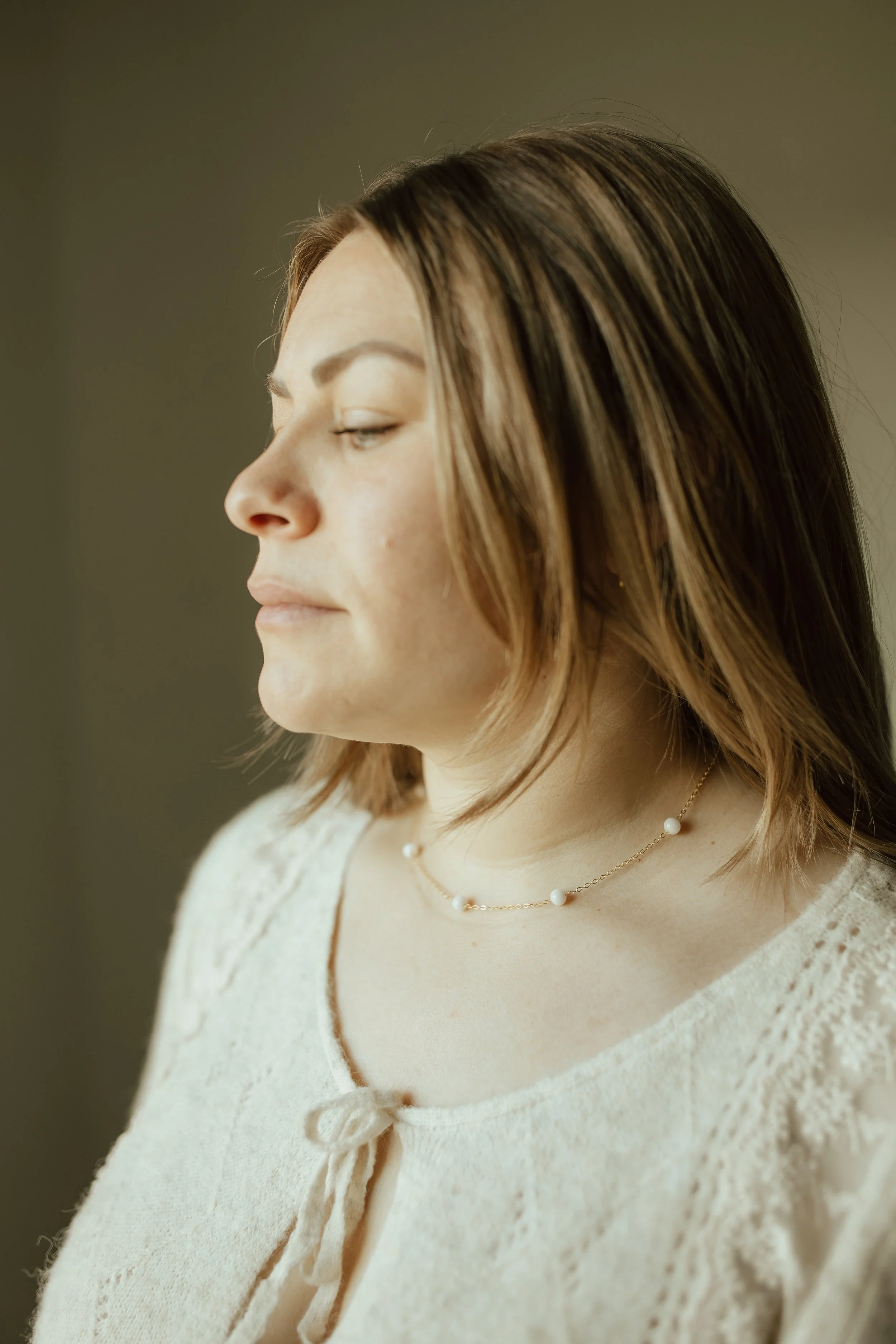 Woman wearing a yellow gold petite pearl choker with 6 pearls spaced out