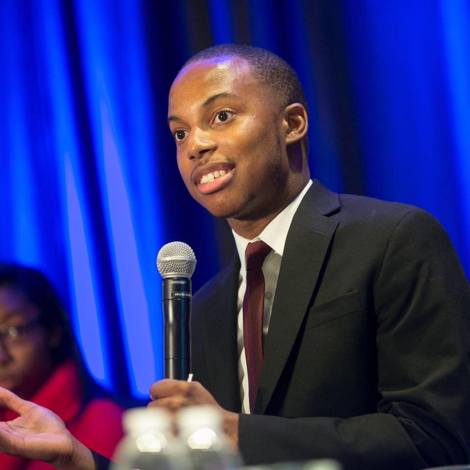 Photo of Jacob Smith holding a microphone while speaking