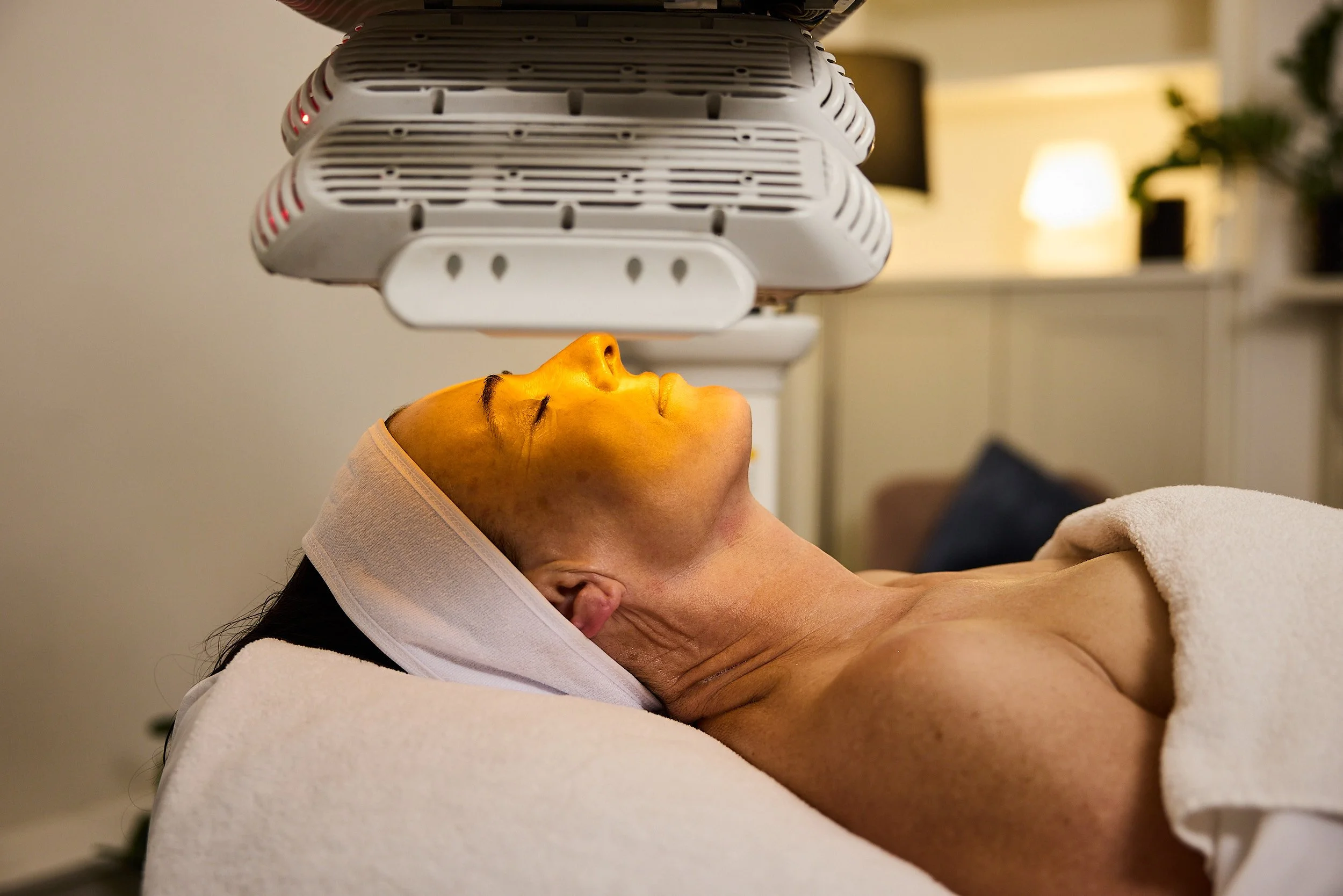 Client of St. Skin in North Melbourne laying on clinic bed with Healite II LED machine promoting skin healing, reducing inflammation and targeting acne-causing bacteria.