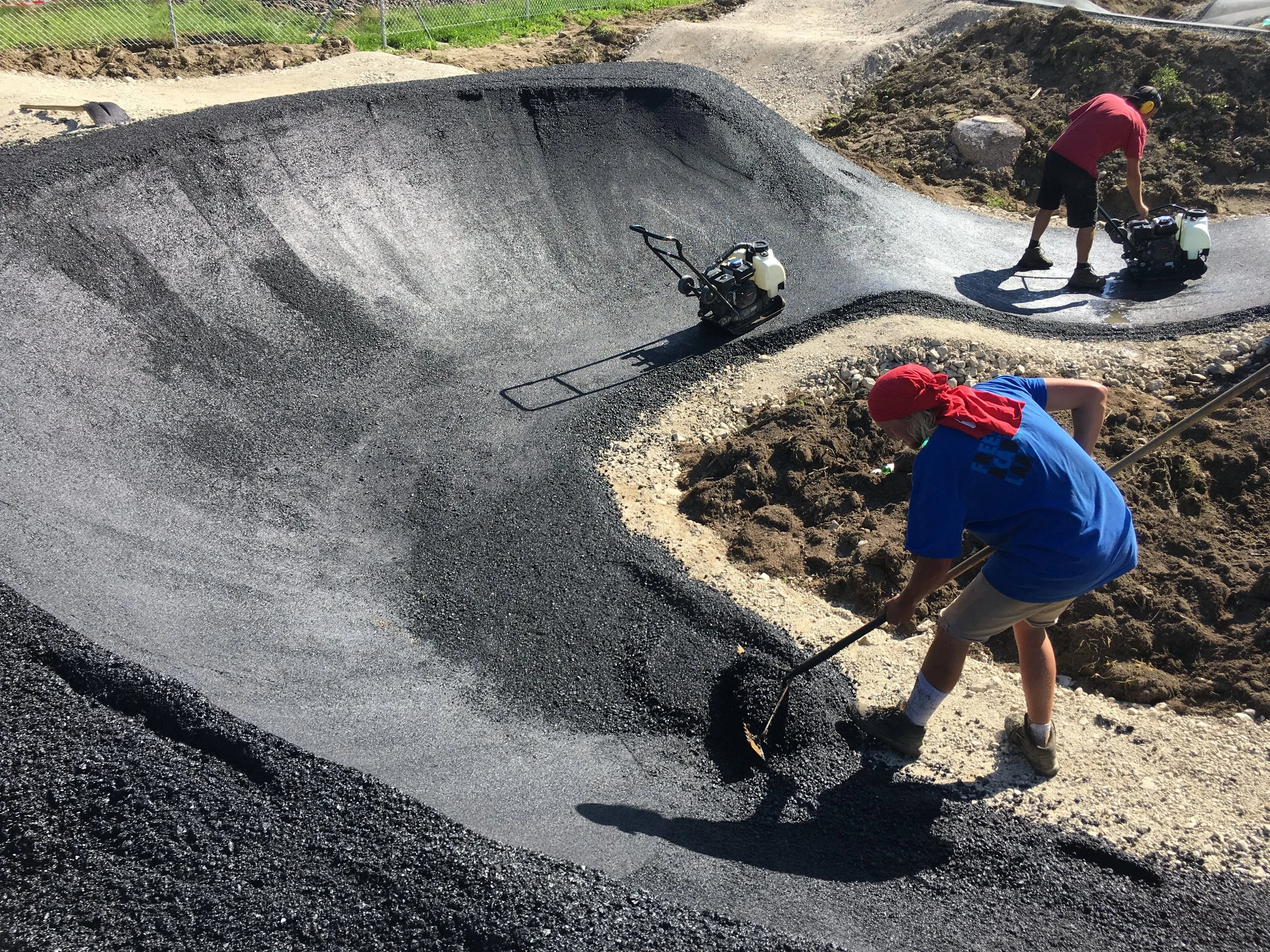 Das grobe Verteilen des Asphalts wird von Hand gemacht