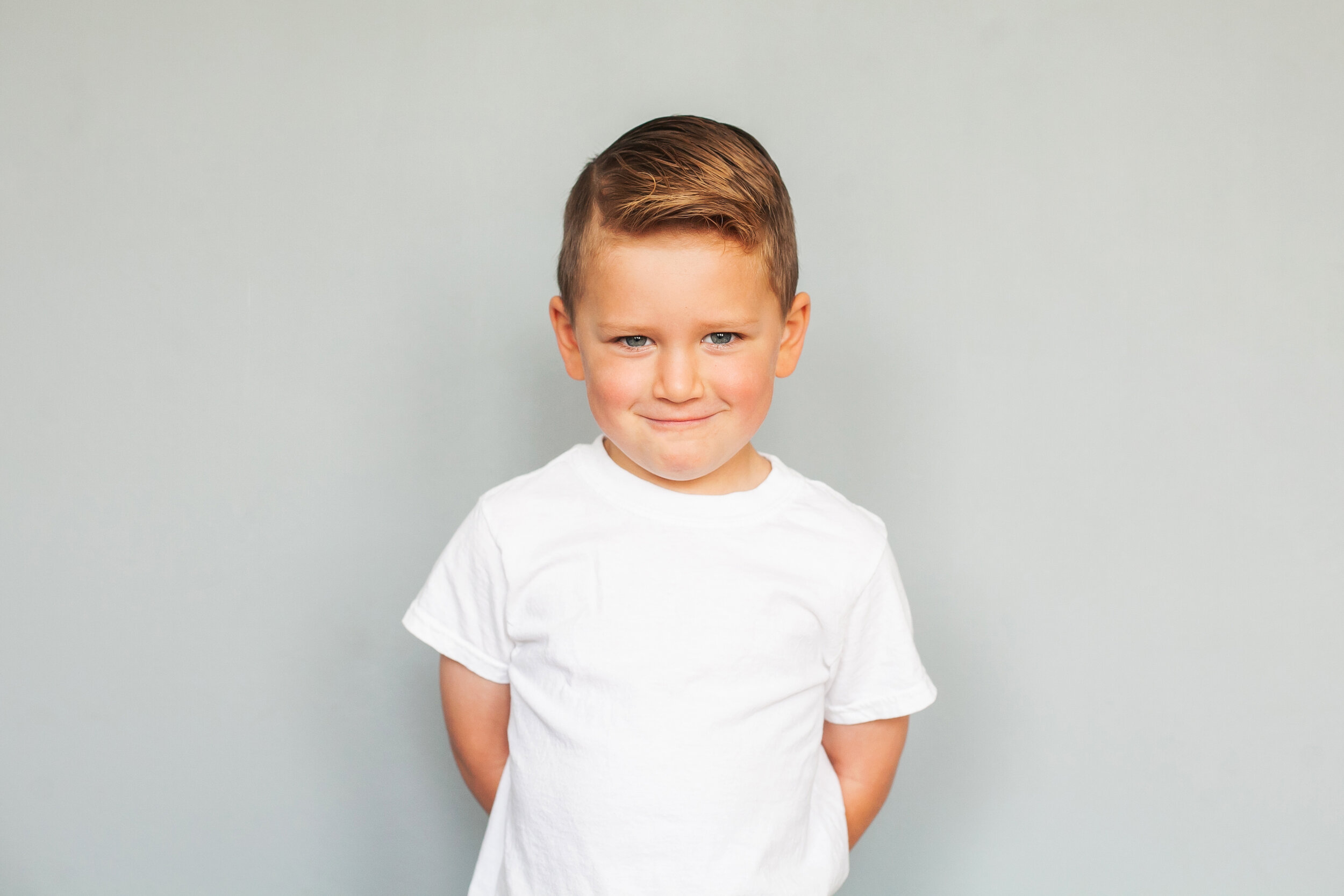 mischievous-boy-children's-portraits-simple-gray-background-white-t-shirt-true-personality-children's-headshots-colleyville-tx