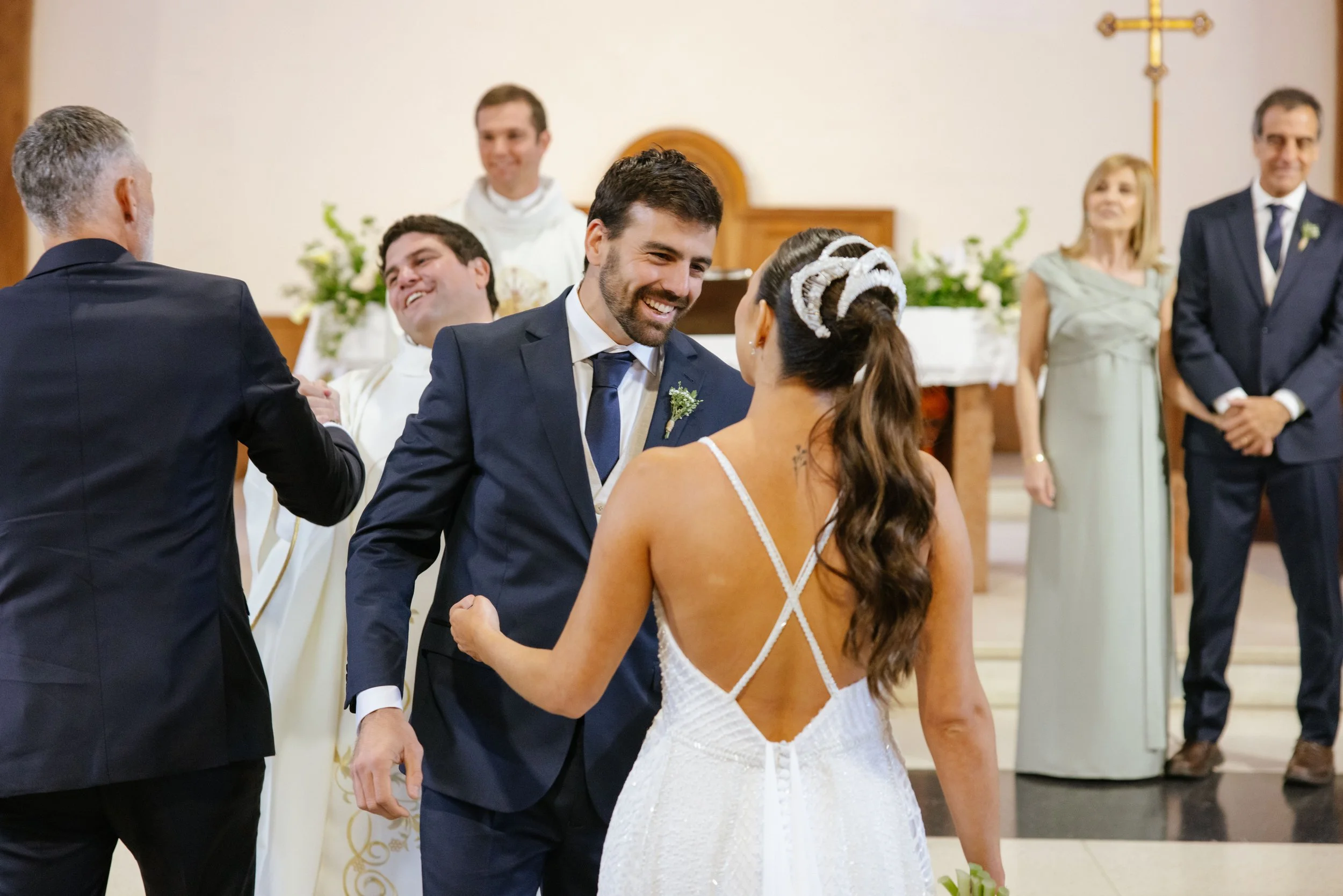 Pareja de novios intercambiando votos en una ceremonia de matrimonio en una iglesia, rodeados de familiares y amigos.