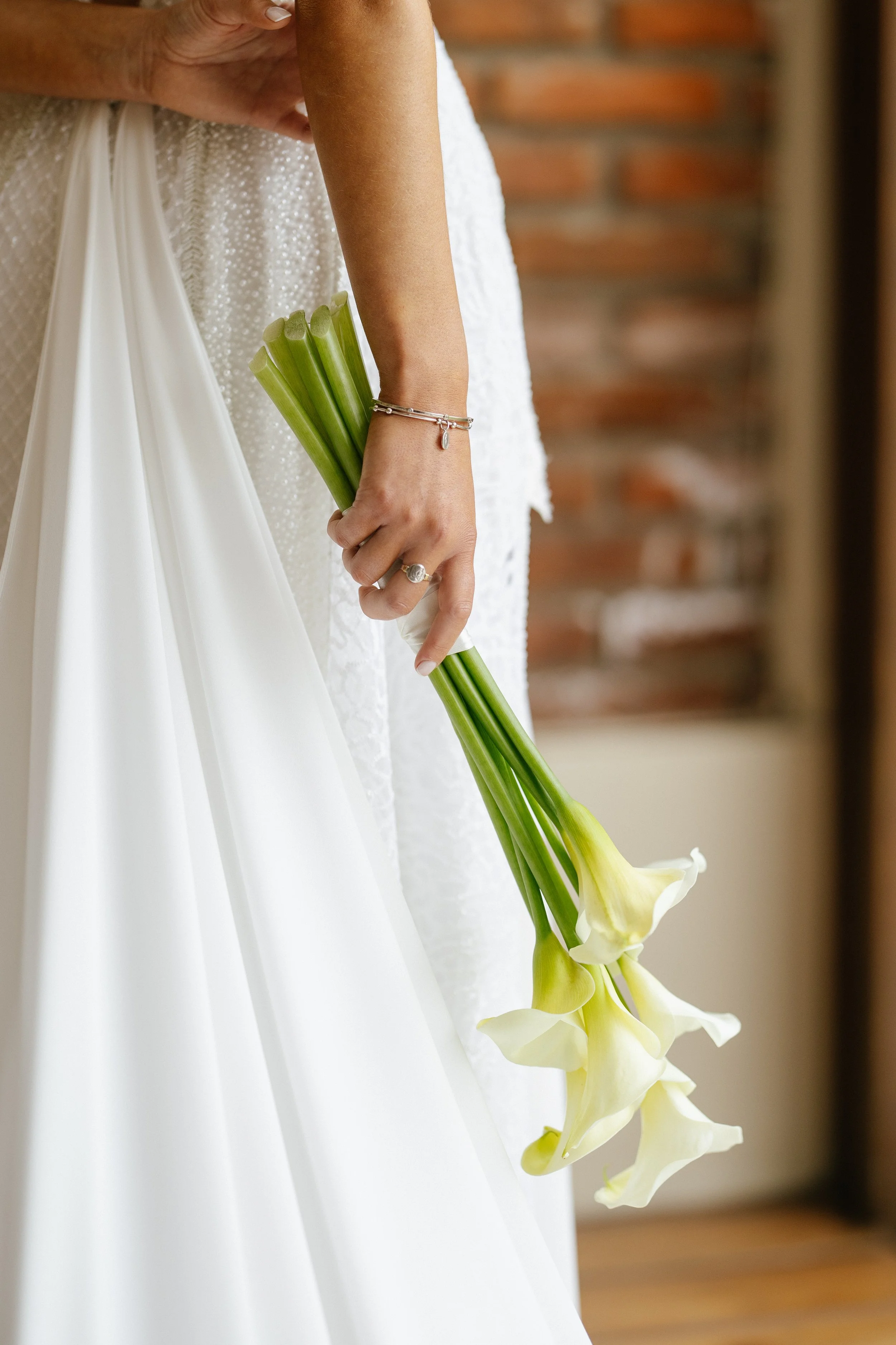 Persona con vestido blanco de novia sosteniendo un ramo de lirios blancos.