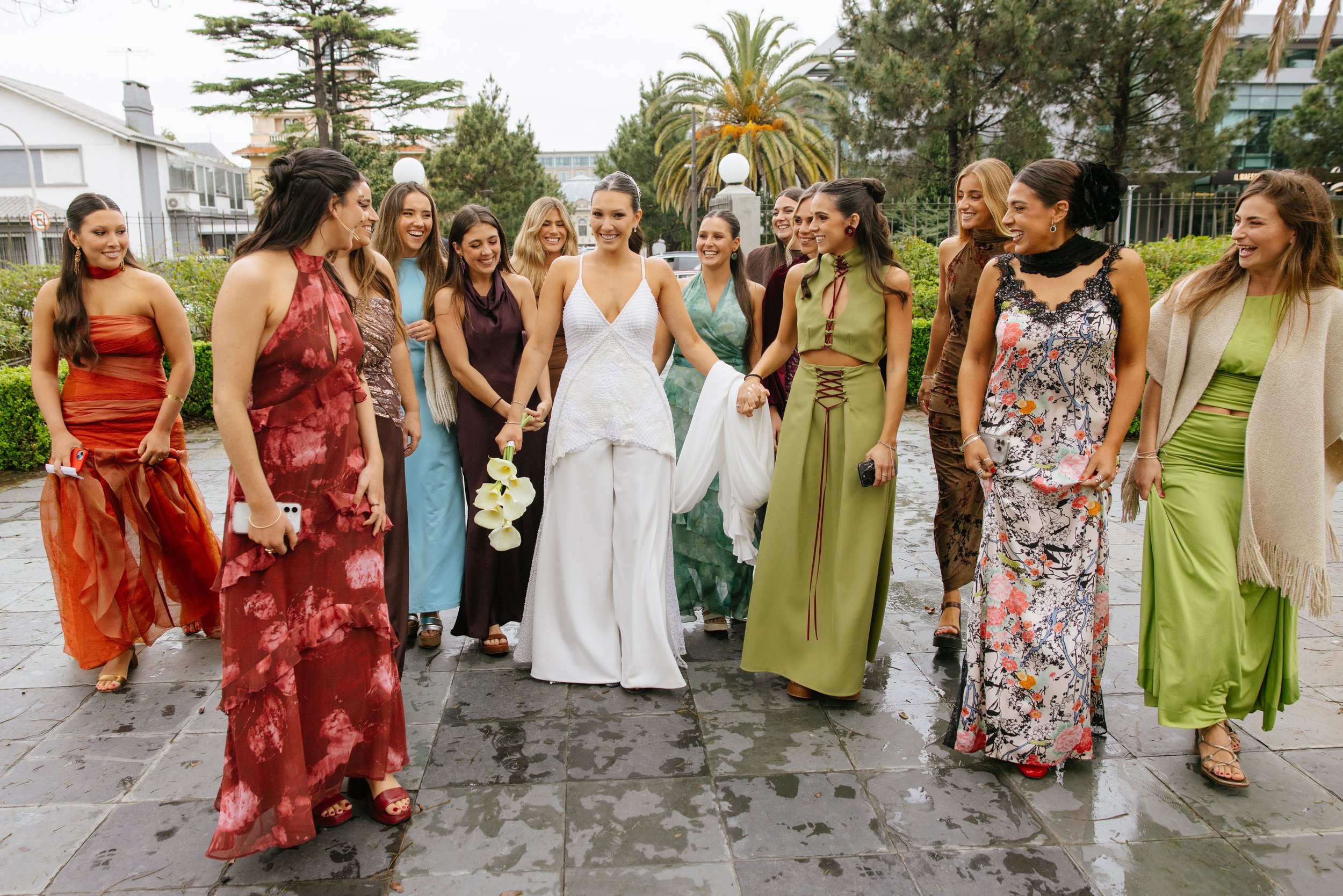Grupo de mujeres vestidas con elegantes vestidos en una terraza al aire libre, sonriendo y conversando.
