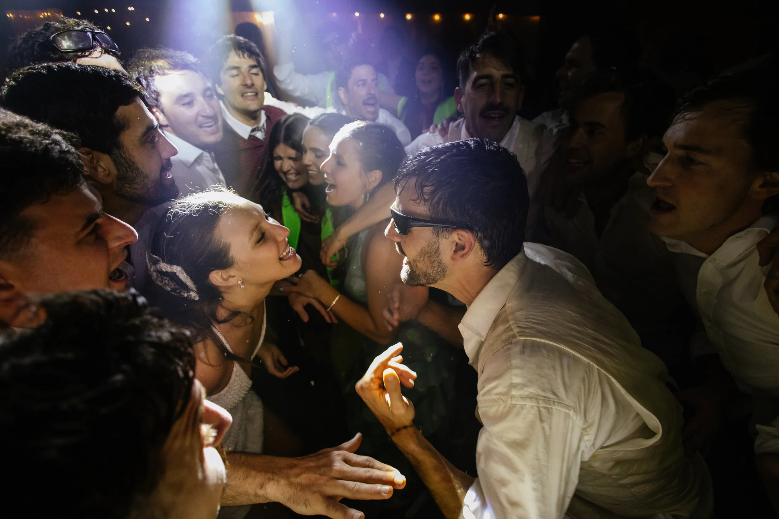 Grupo de personas bailando y disfrutando en una fiesta o celebración, luciendo felices y expresivos.
