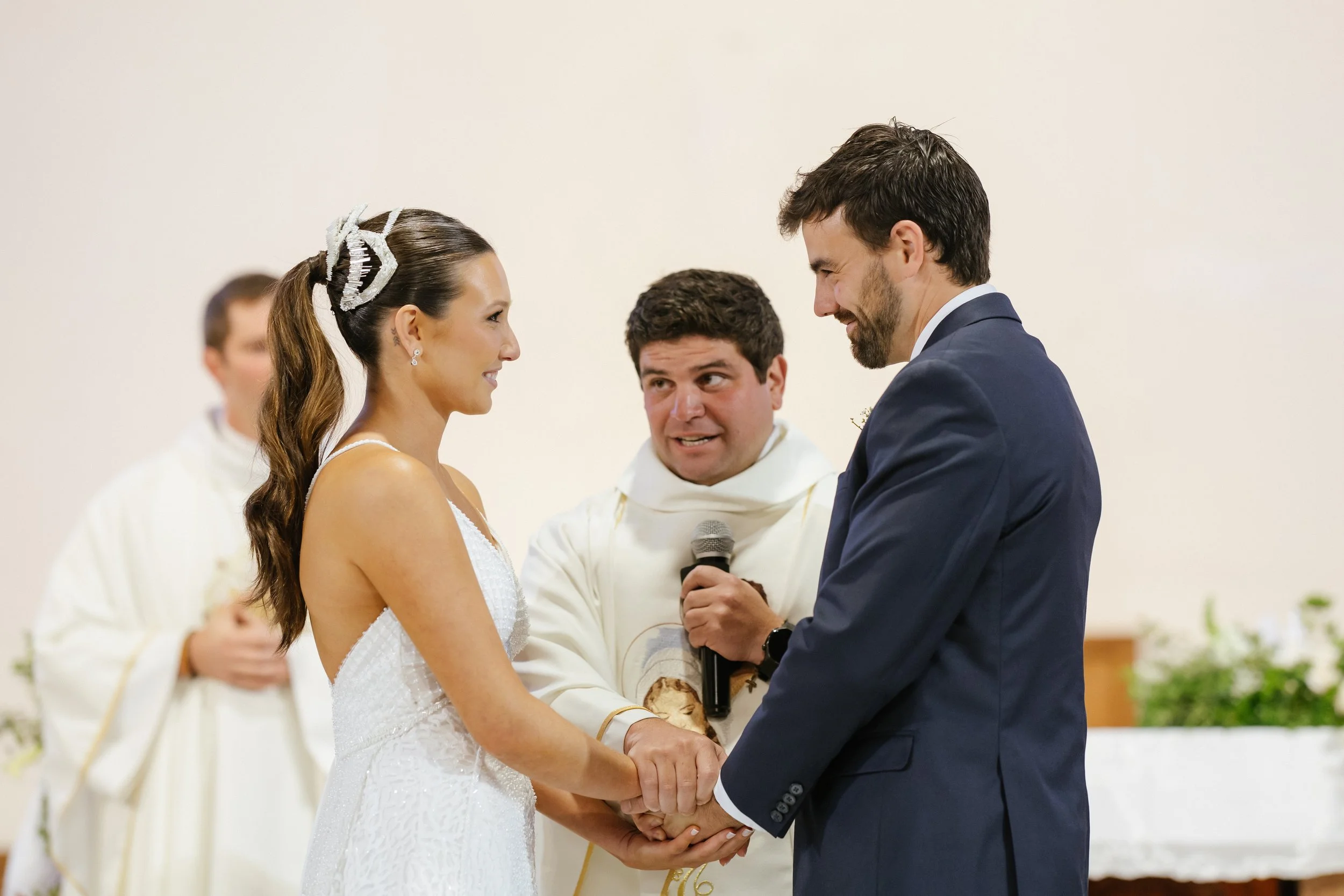 Una pareja se casan en una ceremonia y se miran con felicidad, mientras un oficiante los bendice.