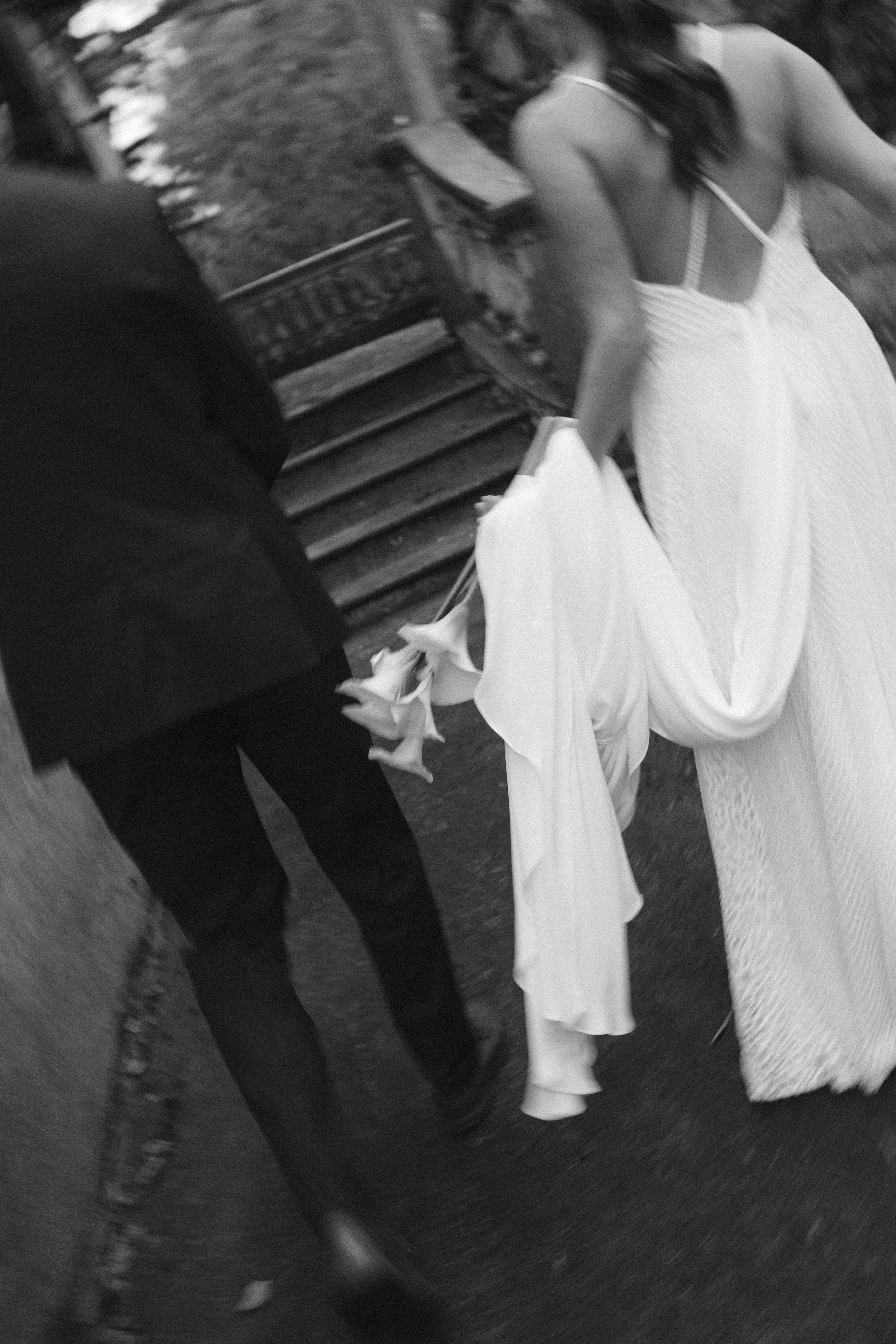 Mujer con vestido blanco, vista de espaldas, en una calle adoquinada