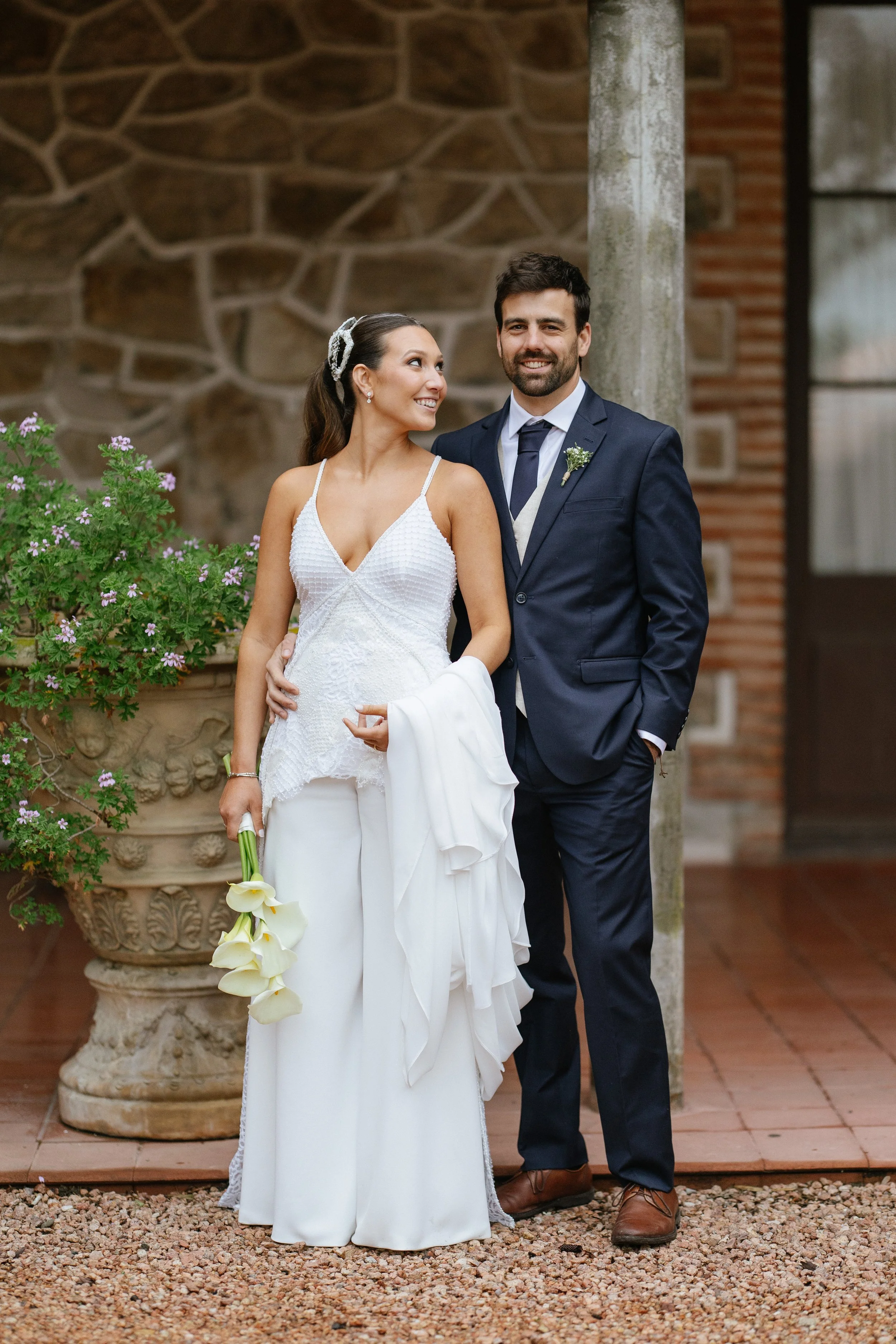 Pareja de novios en boda en un fondo de muro de piedra y plantas