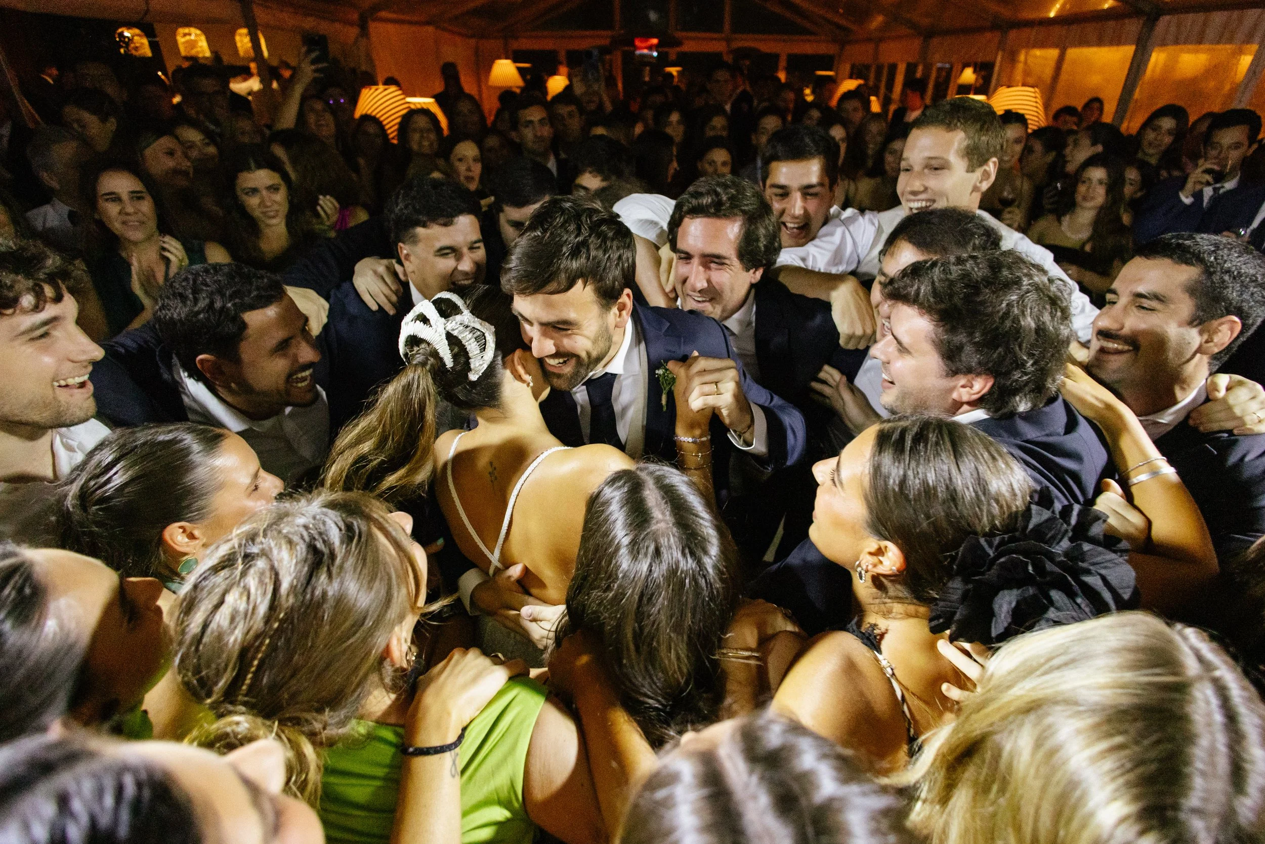 Grupo de personas en una celebración, algunas dando un abrazo y sonriendo.