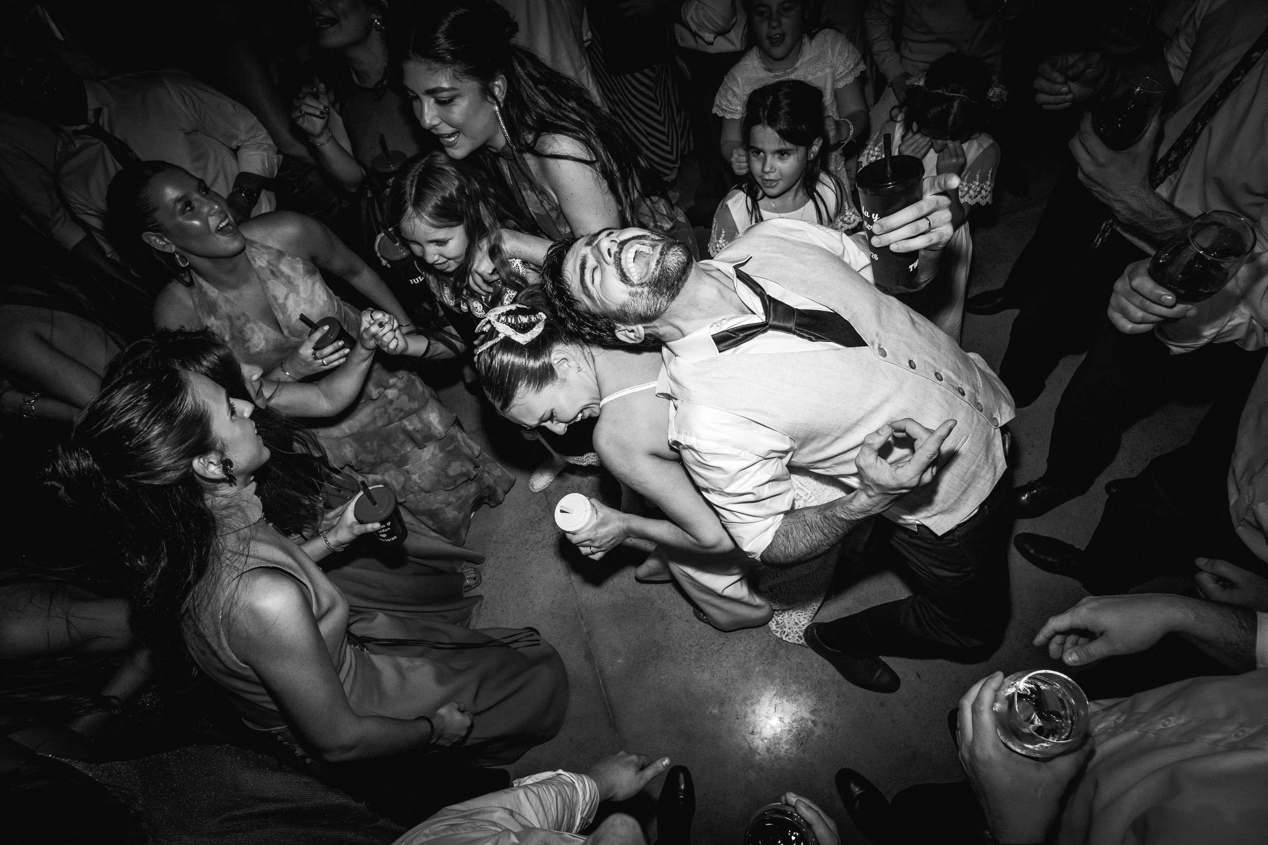Grupo de personas en una fiesta, algunos con bebidas en las manos, riendo y disfrutando en un ambiente social.