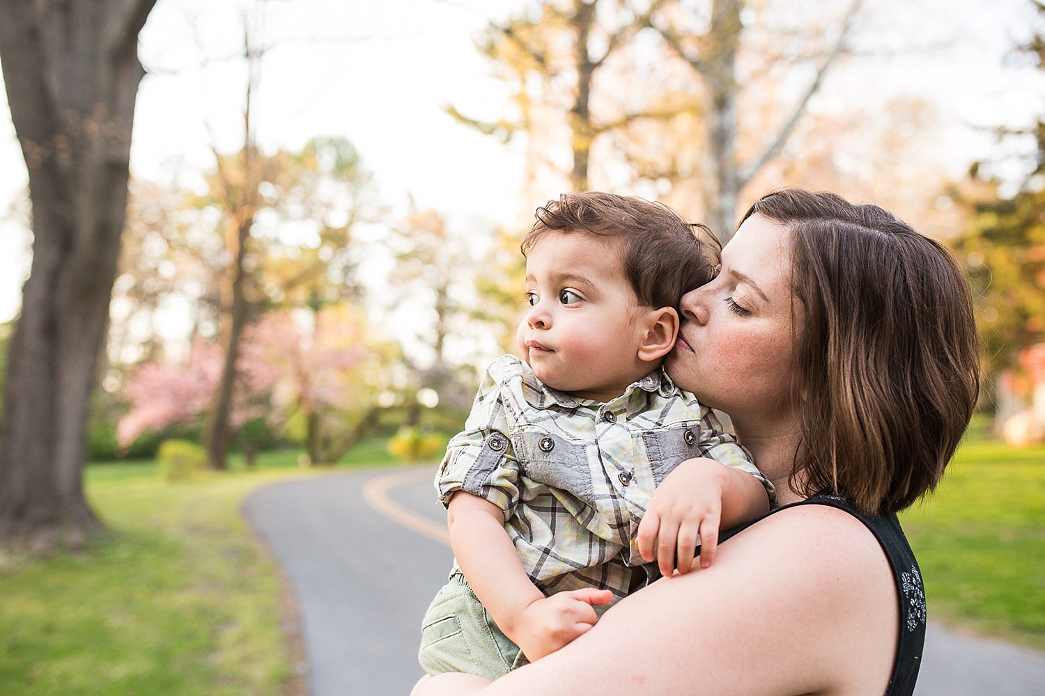  Happy photo of a mother holding her toddler son in front of a flowering cherry tree at Buchmiller Park. 