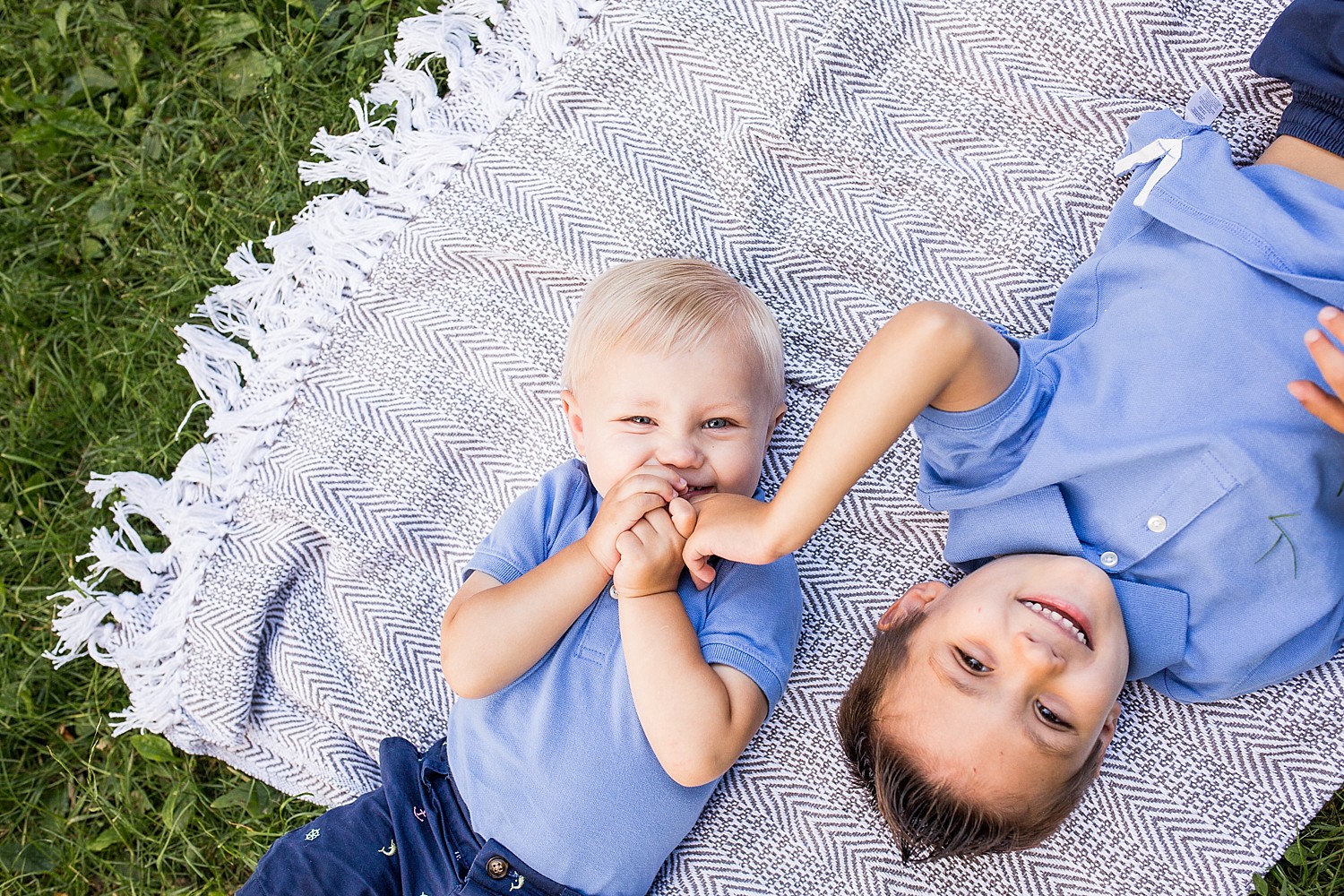  Photo of two little boys laying on a blanket and laughing. 