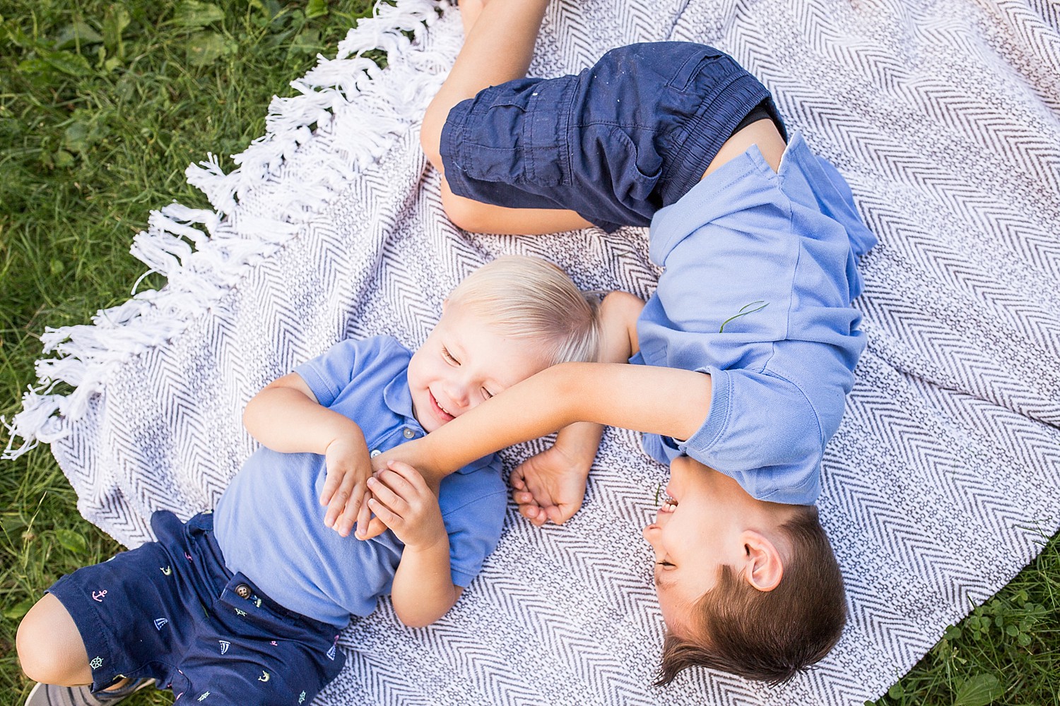  Photo of two little boys laying on a blanket and laughing. 